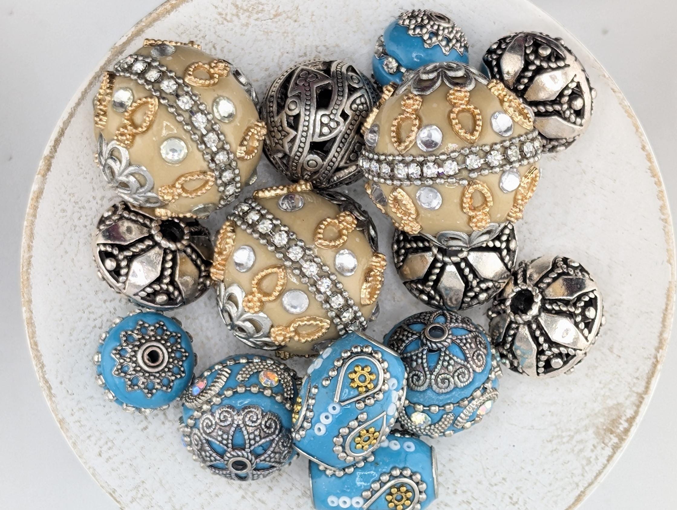 a collection of ornate, decorative beads and beads with intricate designs, including blue and silver elements.