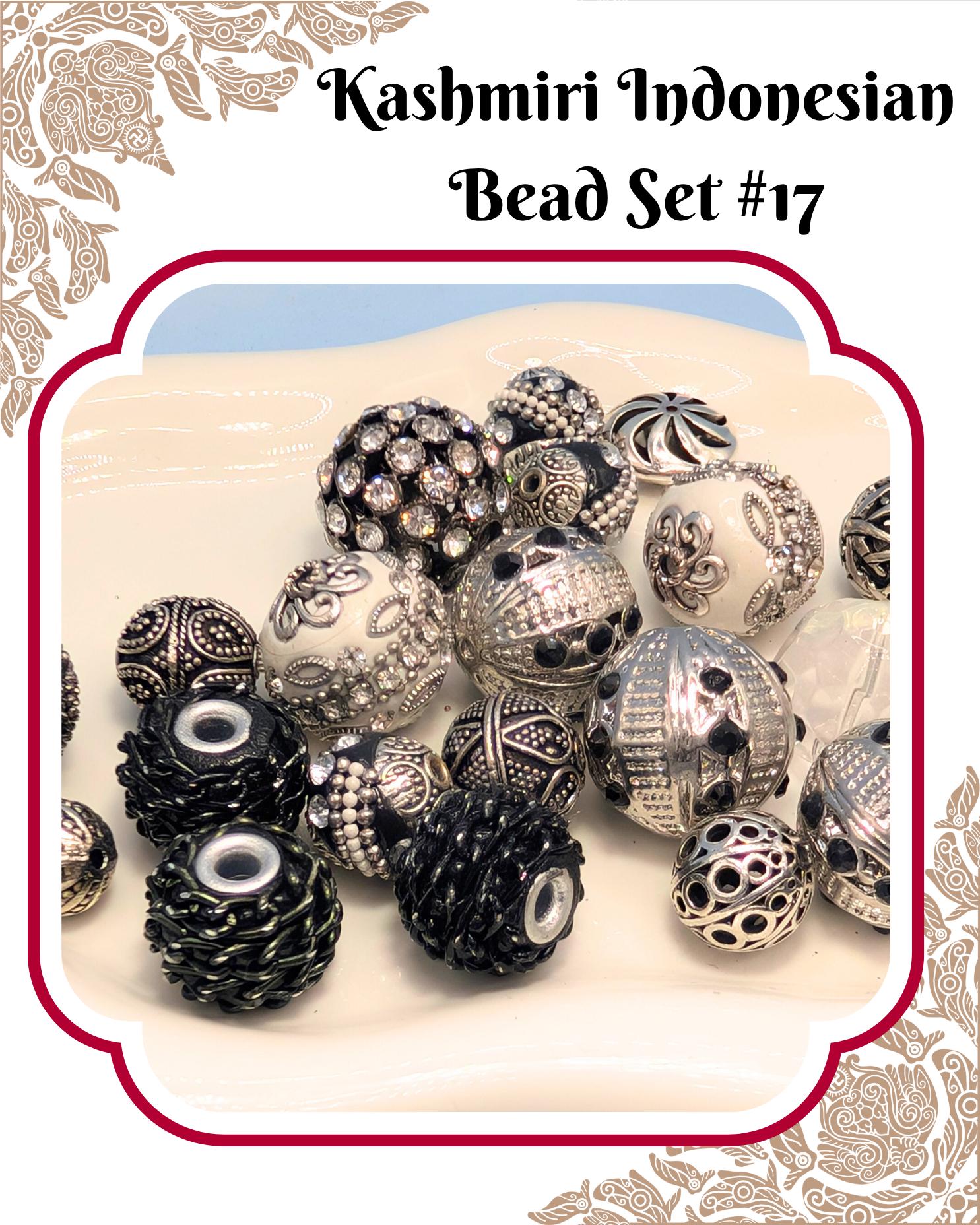 a collection of various beads, including black and silver beads, arranged on a white surface. The beads appear to be of different shapes and sizes, creating an interesting and visually appealing display.