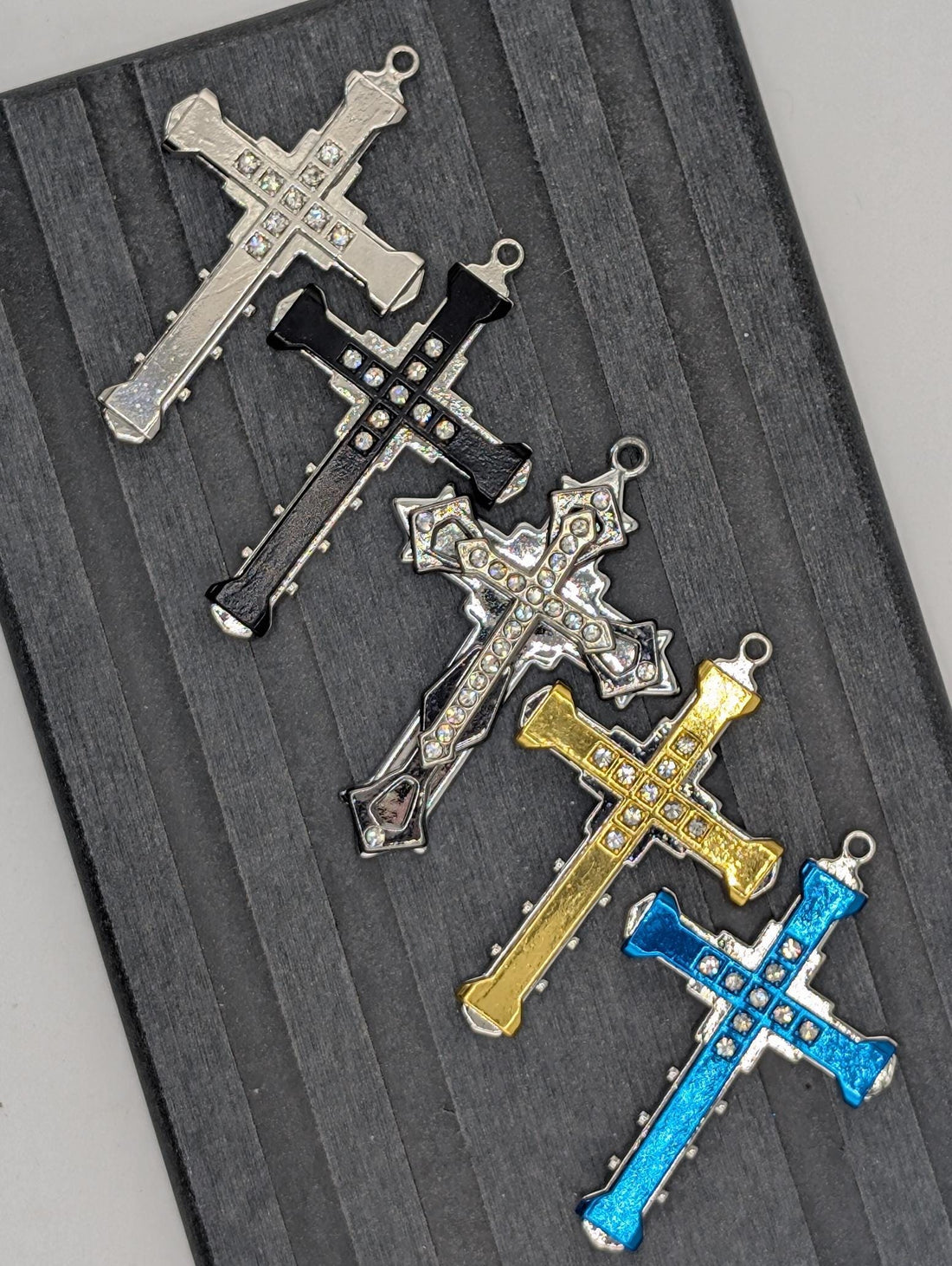 a collection of ornate crosses, each adorned with a sparkling crystal or gemstone. The crosses are arranged in a row, showcasing their intricate designs and the vibrant colors of the gemstones.