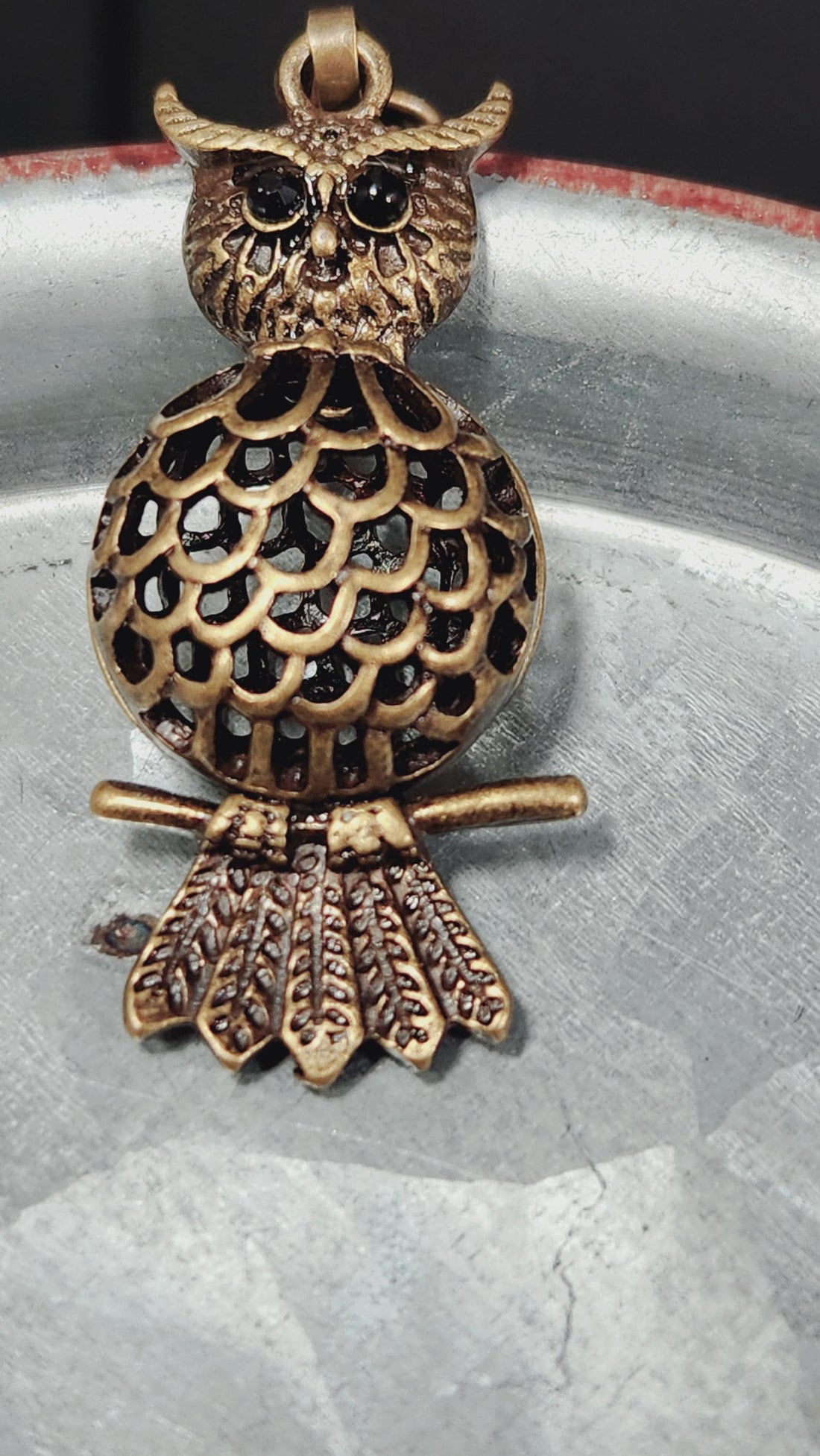 A close-up view of a decorative metal piece, possibly a necklace or bracelet, with a chain and a small, ornate pendant or charm.