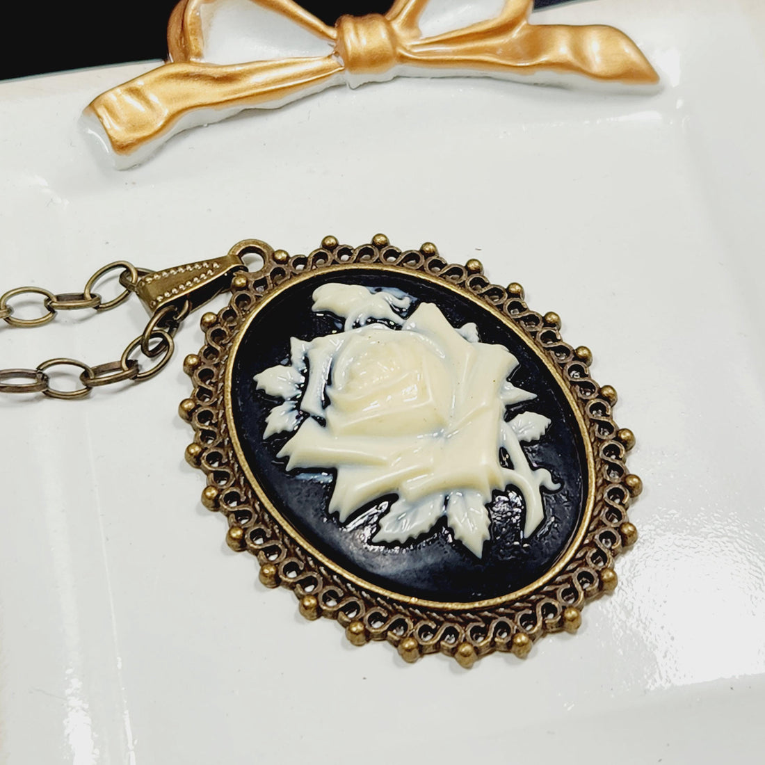 A decorative pendant with a floral design and a gold-colored ribbon.