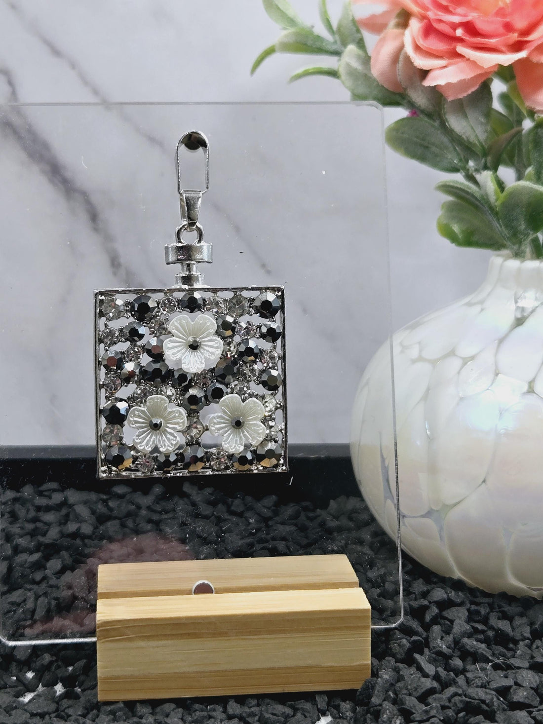 a silver-colored keychain with a decorative metal frame, adorned with small, clear rhinestones or crystals.