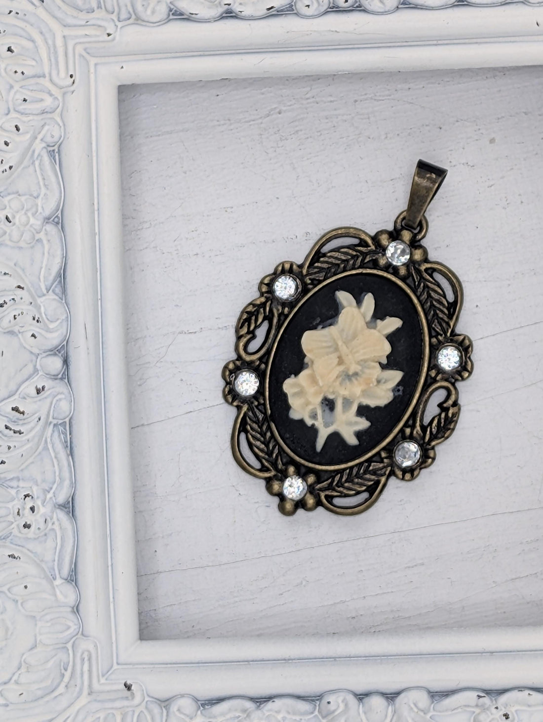 A decorative pendant with a floral design and a chain is shown in the image.