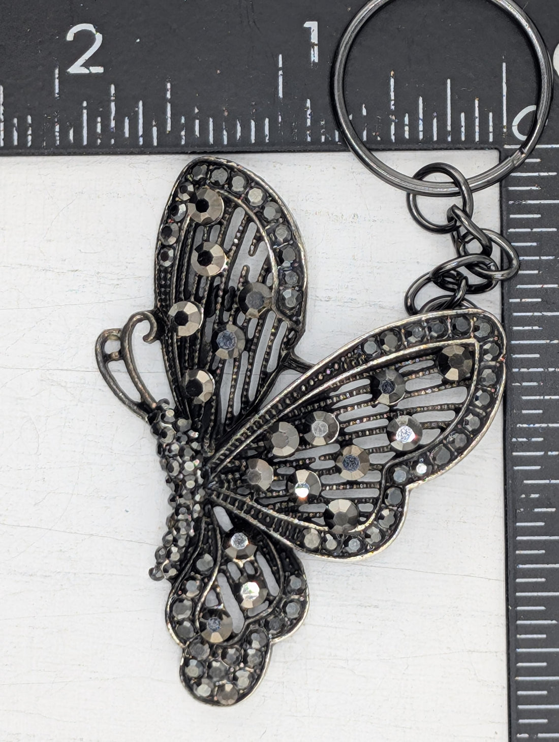 A decorative butterfly-shaped pendant with intricate metalwork and sparkling gemstones.