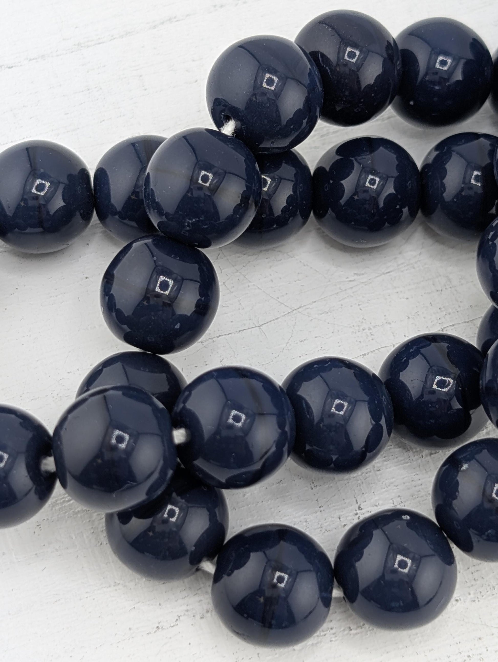 A collection of dark blue beads arranged in a circular pattern on a white surface.