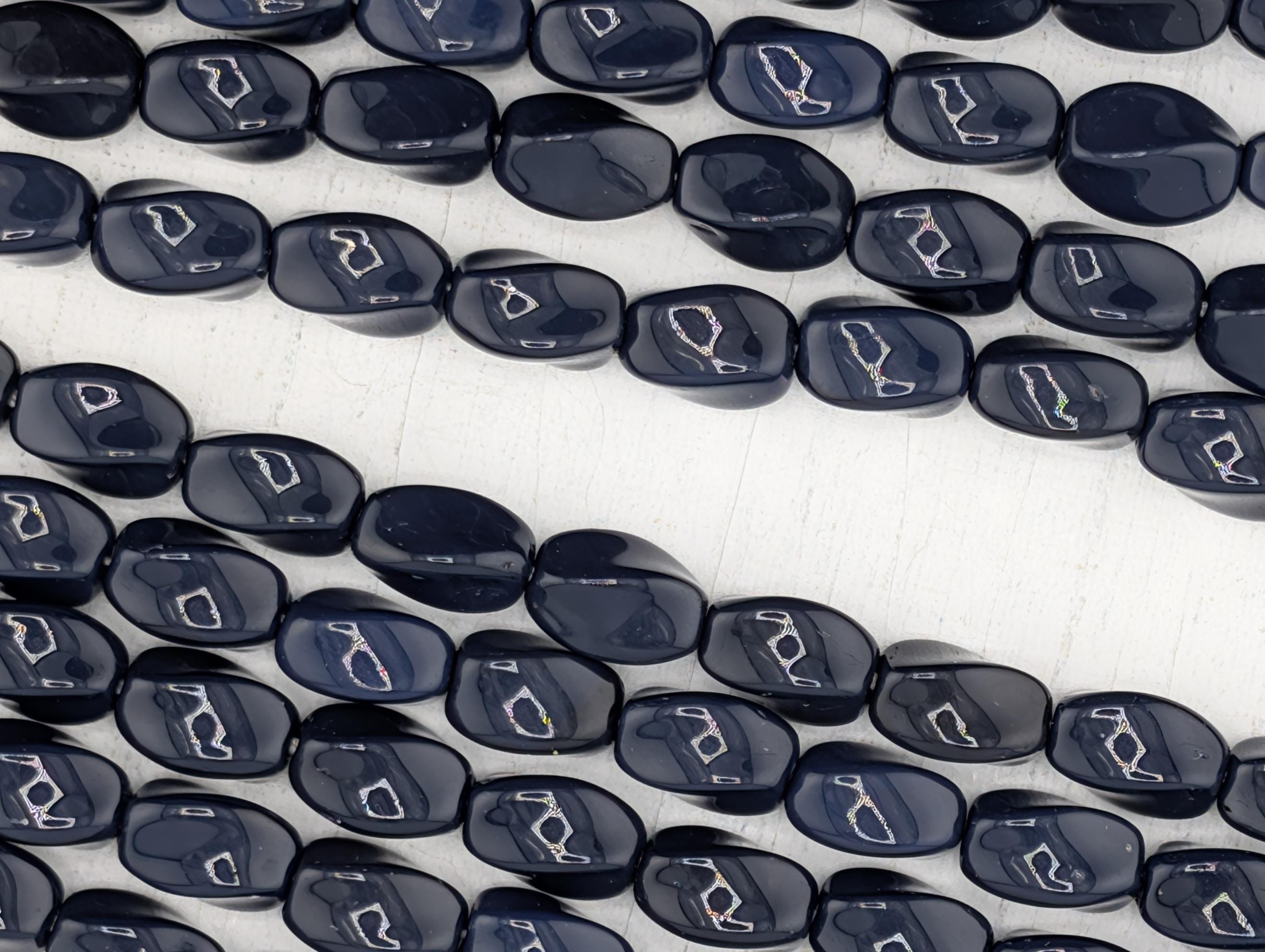 a close-up view of numerous dark blue beads arranged in a pattern, with some of the beads overlapping each other.