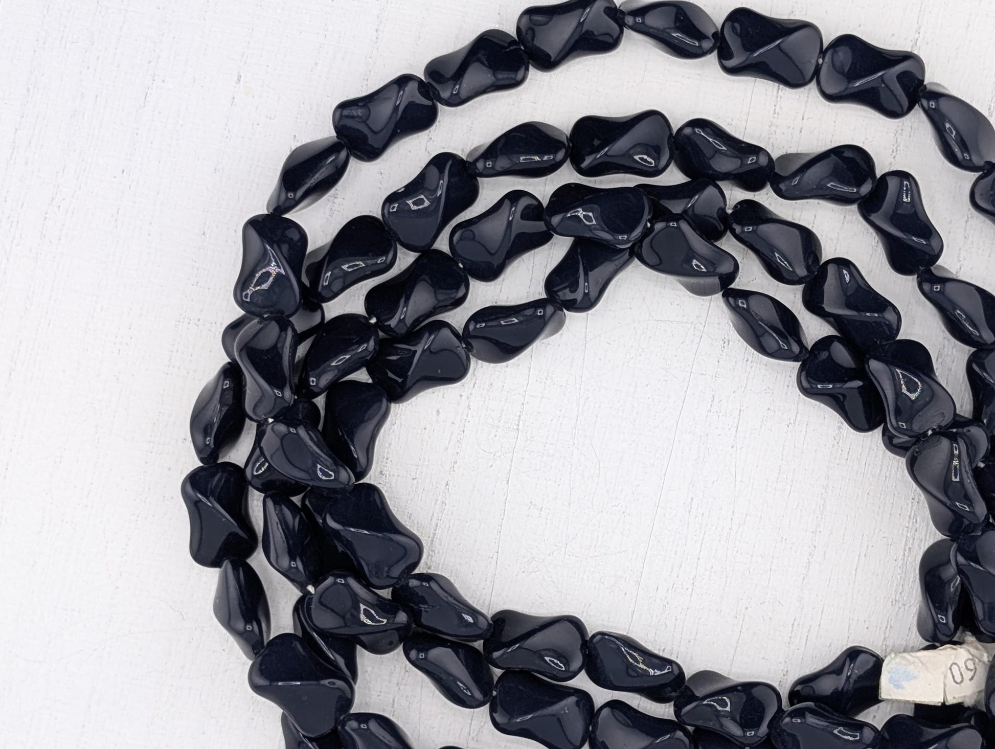 A close-up view of a collection of black beads arranged in a circular pattern on a white background.