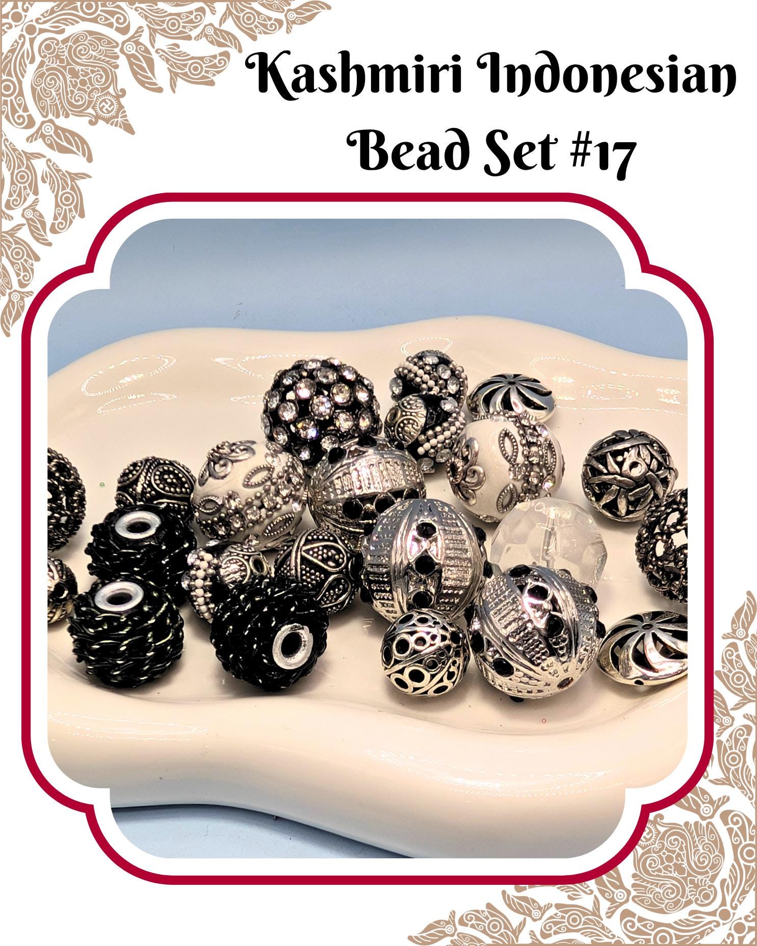 A collection of various beads, including silver, black, and white beads, arranged on a white surface.