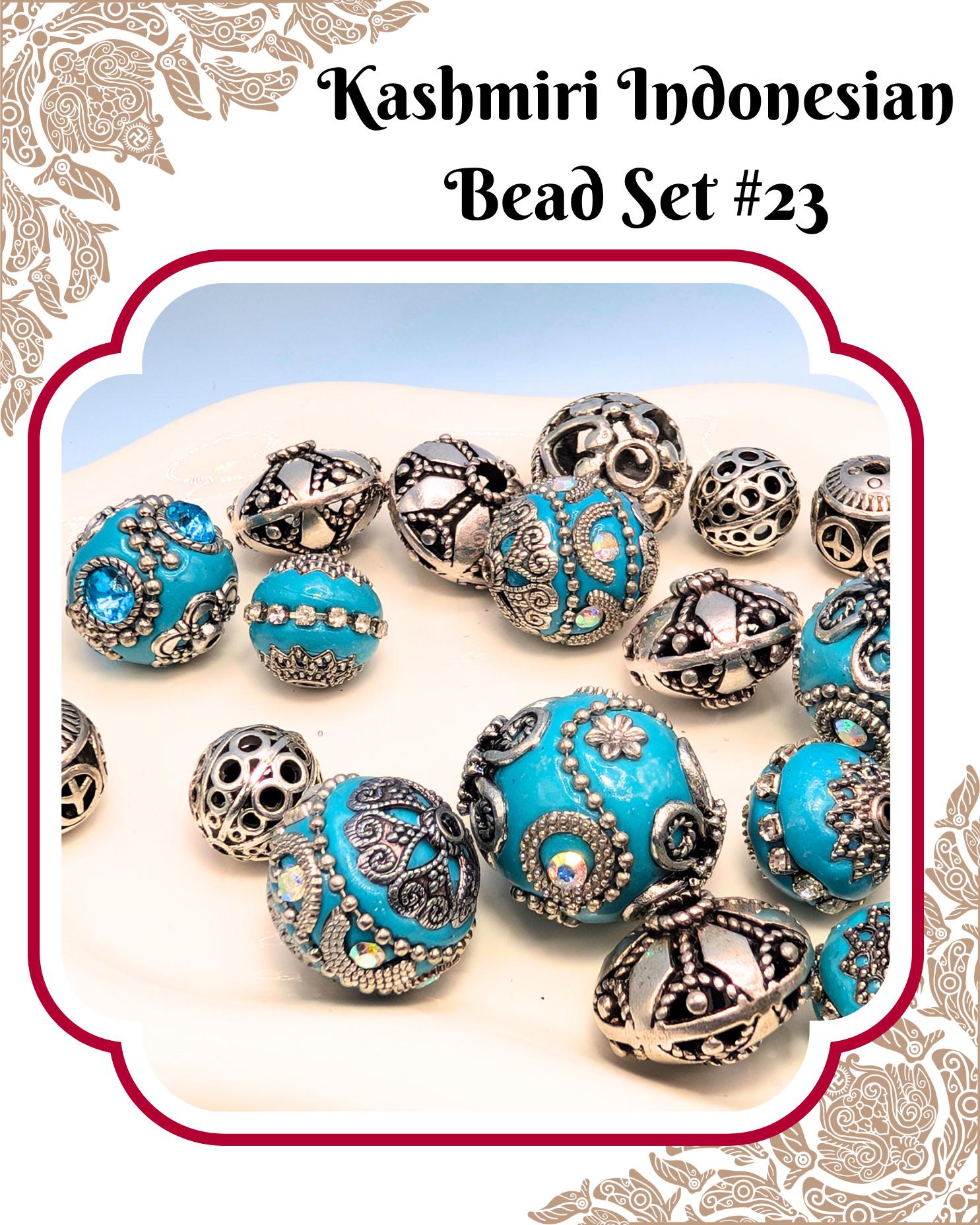 A collection of intricately designed blue and silver beads, including various shapes and patterns, arranged on a white surface.