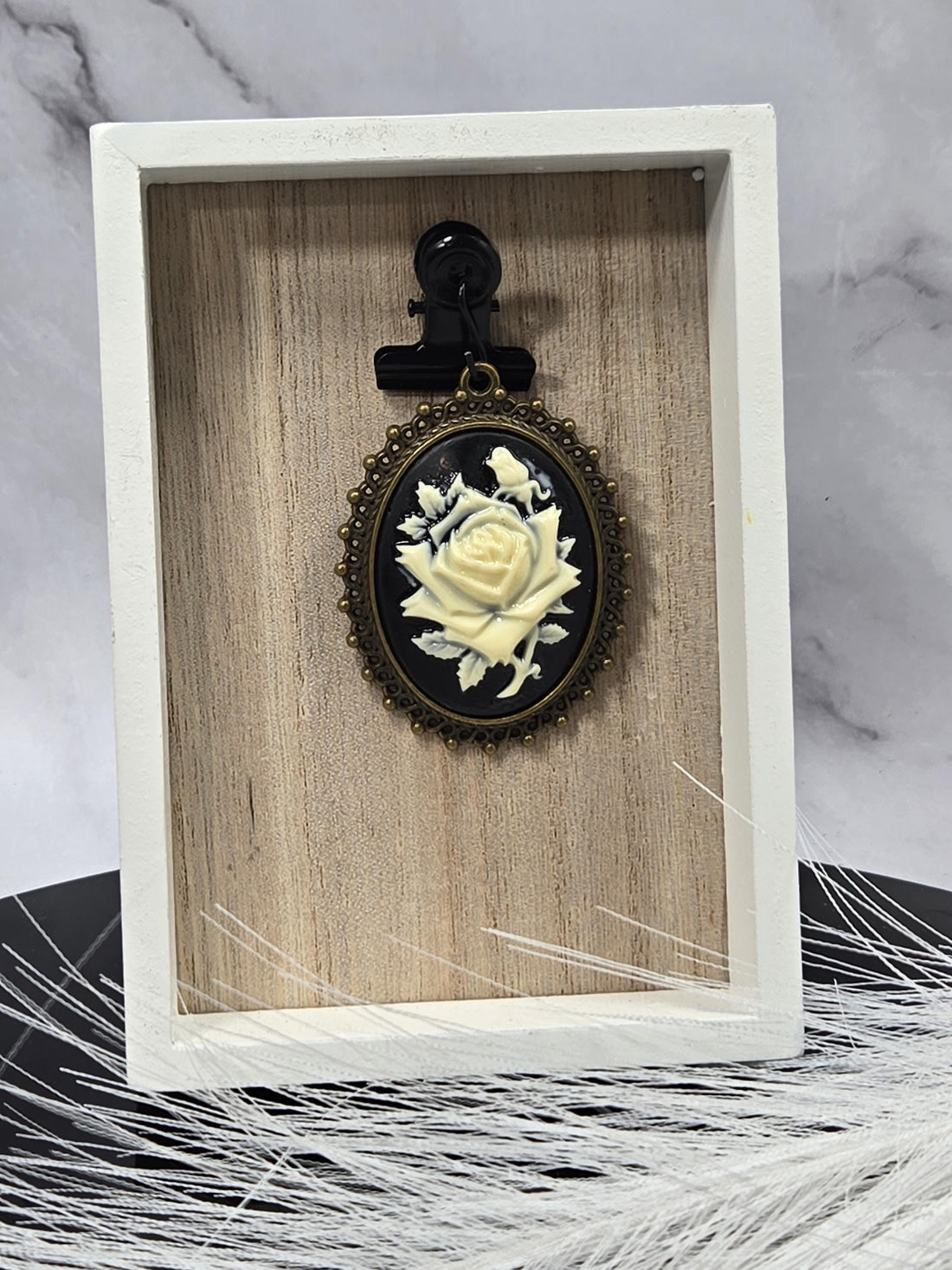 A decorative pendant with a floral design and a gold-colored ribbon.