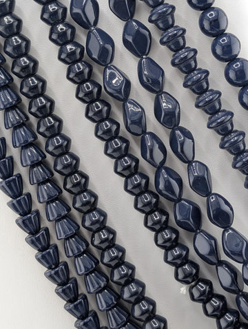 a collection of dark blue beads arranged in rows, showcasing various shapes and sizes.