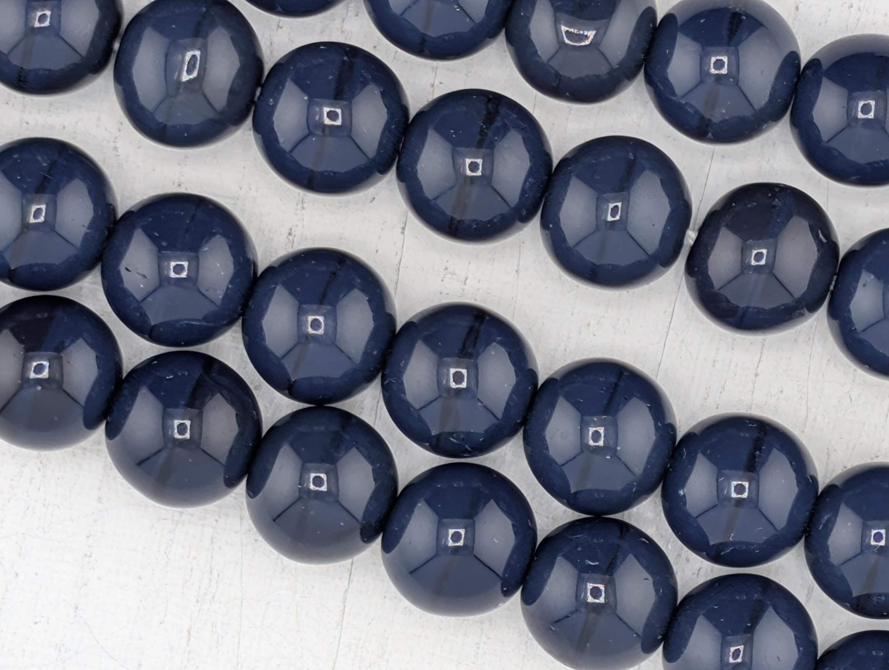 A collection of dark blue glass beads arranged in a circular pattern on a white background.