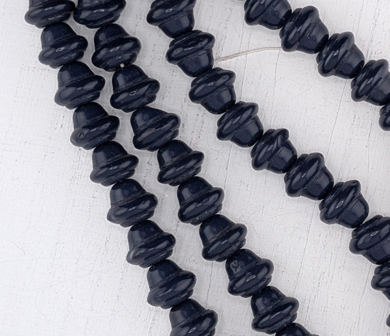A close-up view of a collection of dark blue beads arranged in a row on a white surface.