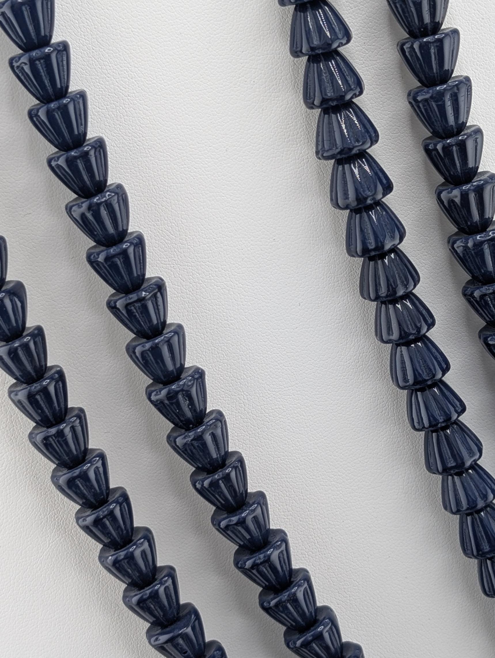 a close-up view of a collection of dark blue beads arranged in a row, with a white background.
