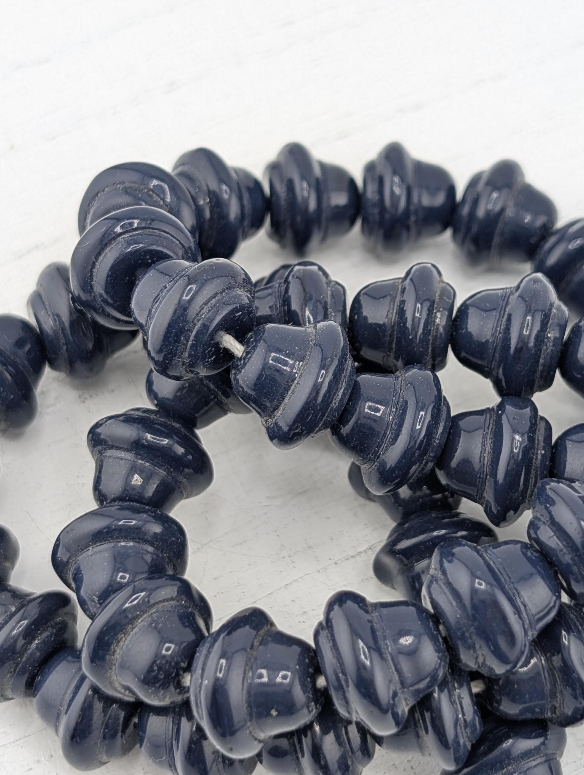 A close-up image of a collection of dark blue, spiral-shaped beads arranged in a circular pattern.