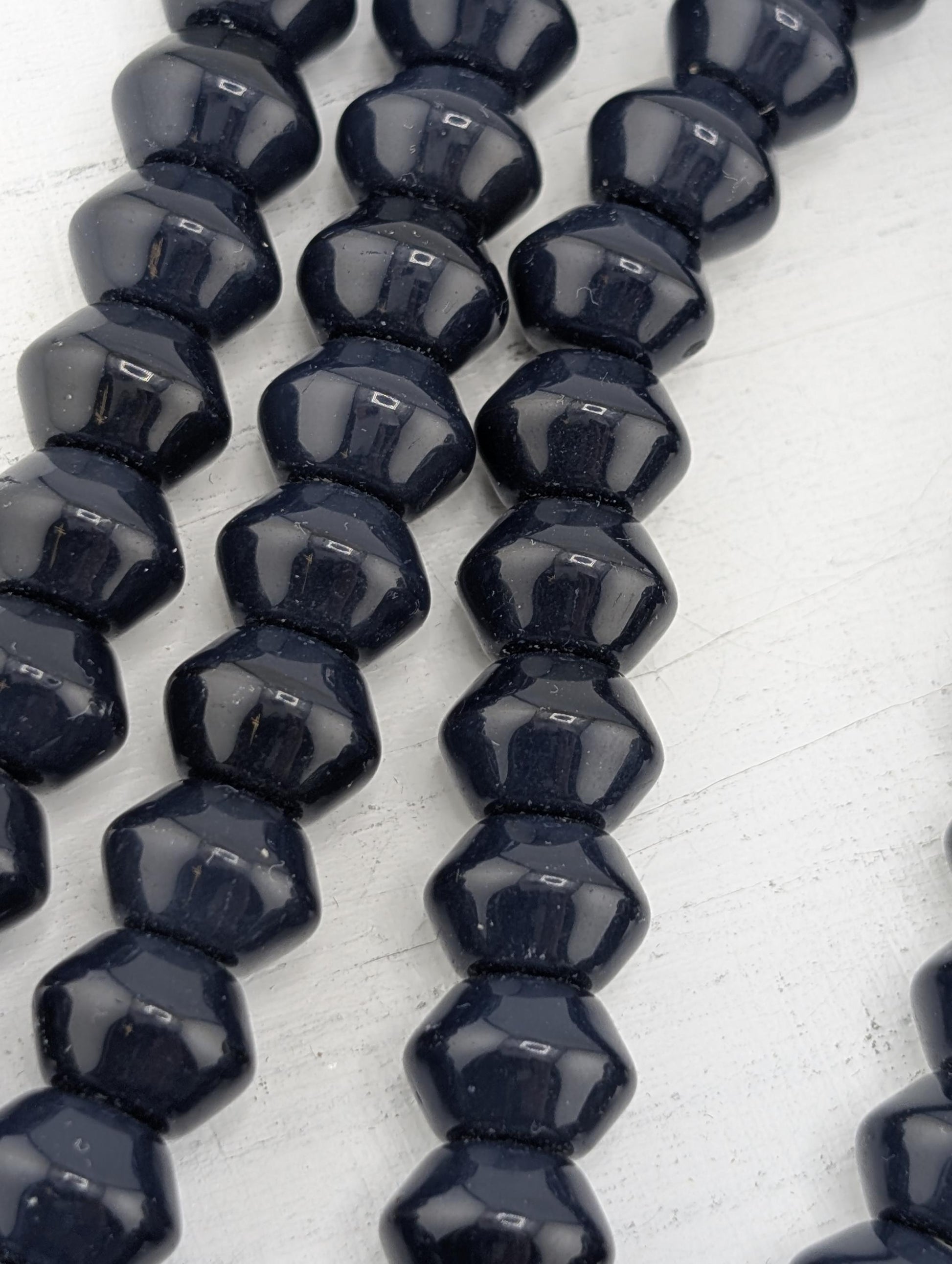 A close-up image of a collection of dark blue, shiny beads arranged in a row.