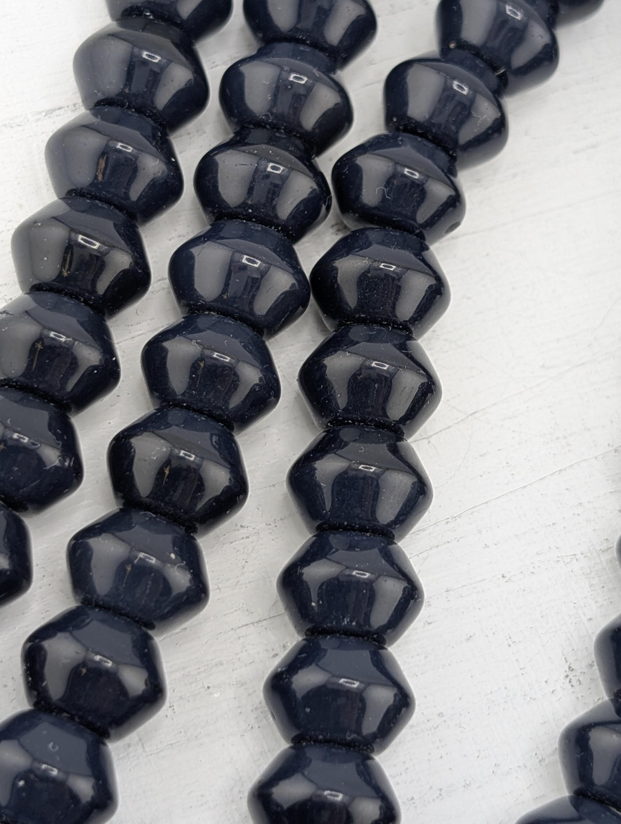 A close-up image of a collection of dark blue, shiny beads arranged in a row.