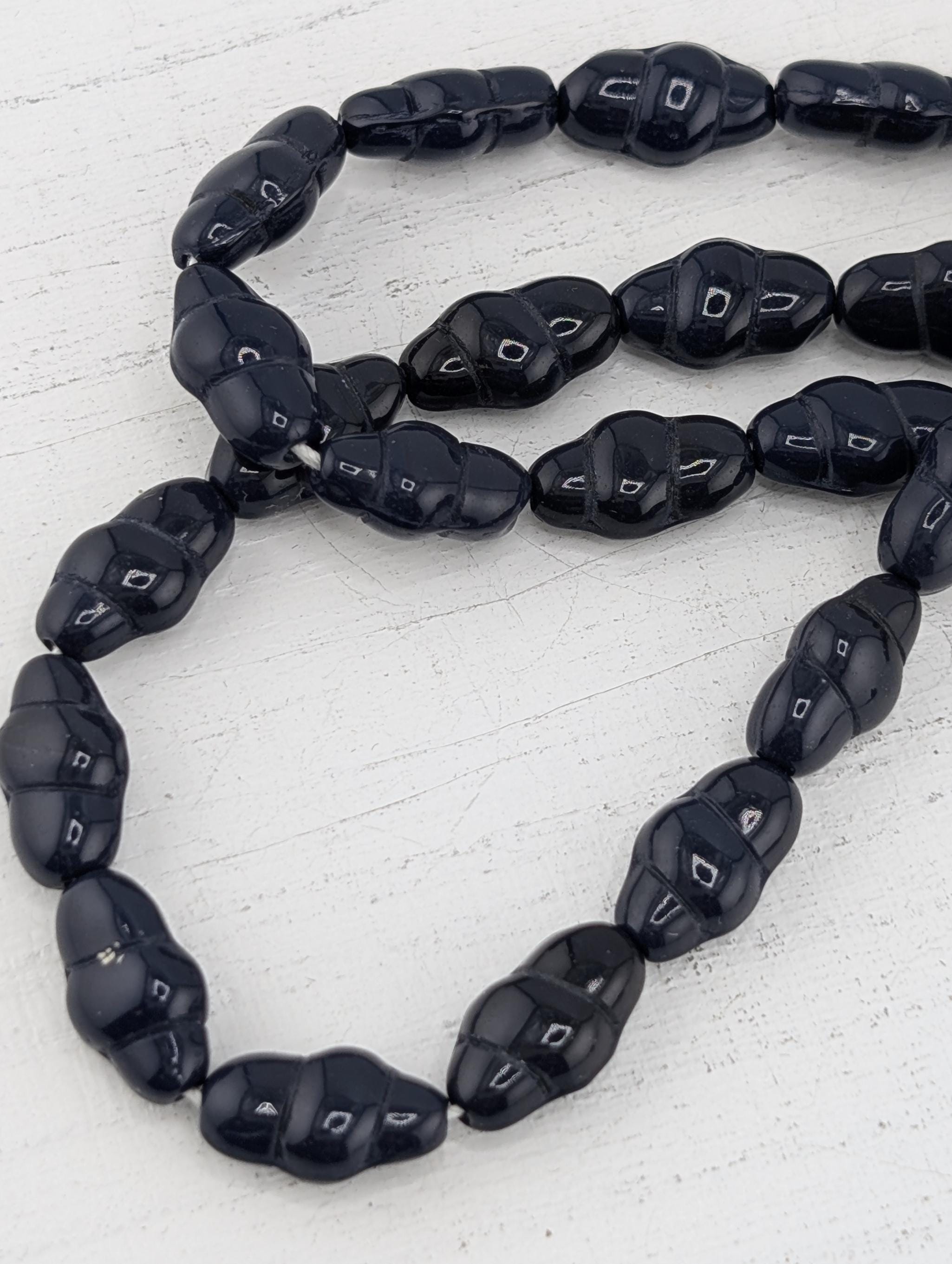 A close-up image of a collection of black beads arranged in a row on a white surface.
