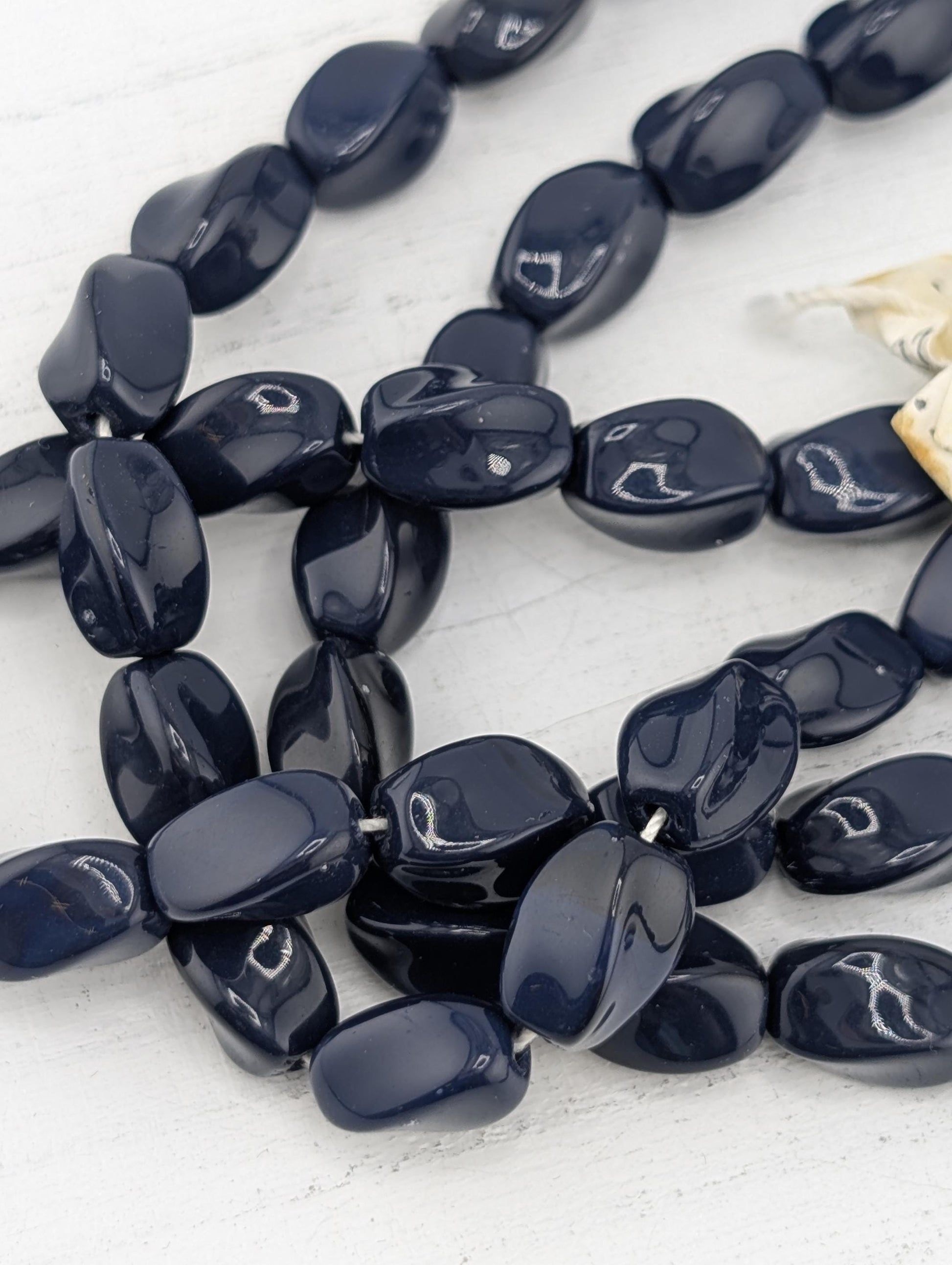A collection of dark blue beads arranged in a loose, tangled pattern on a white surface.