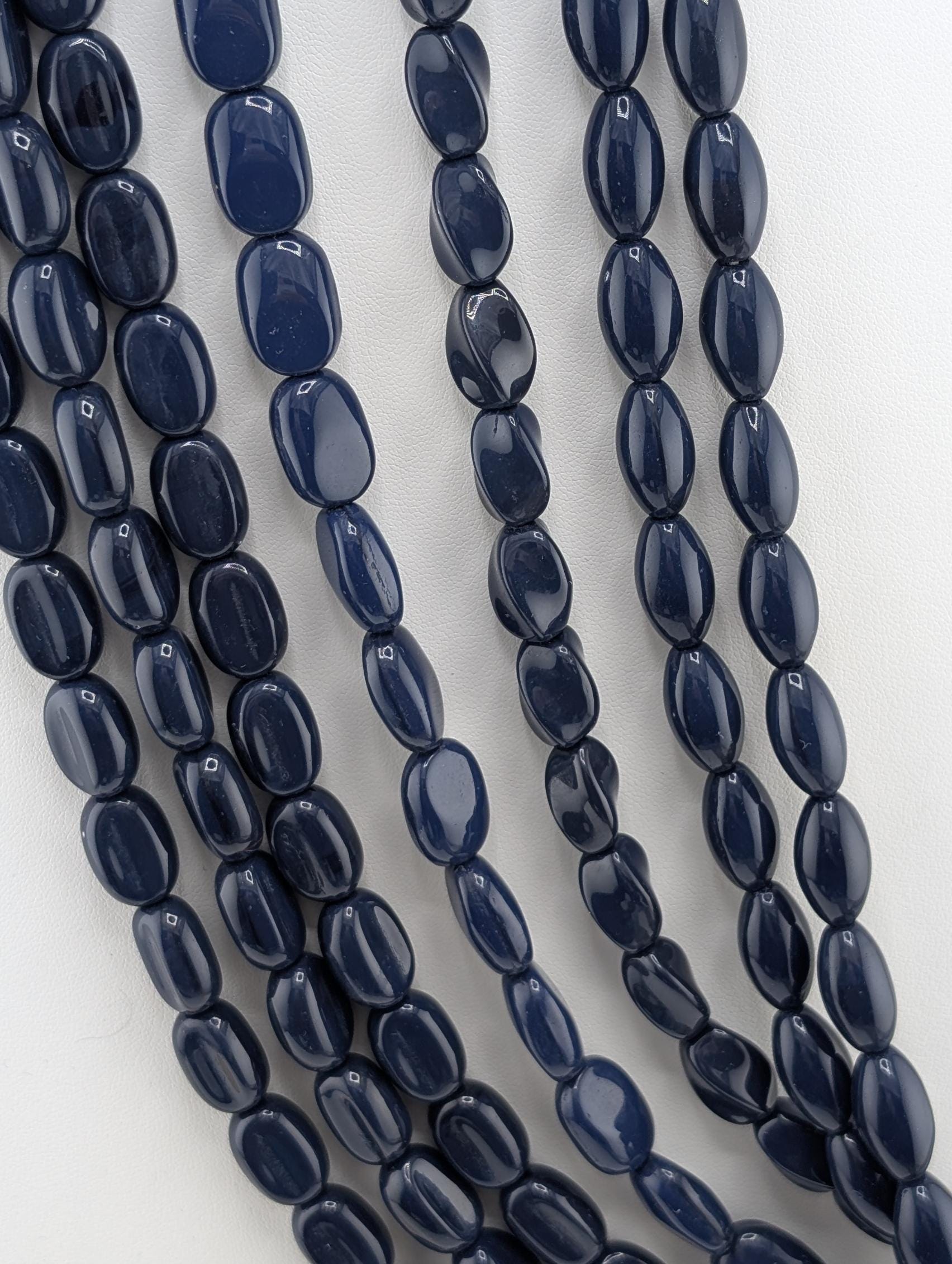 A collection of dark blue beads arranged in a row, with some beads overlapping each other.