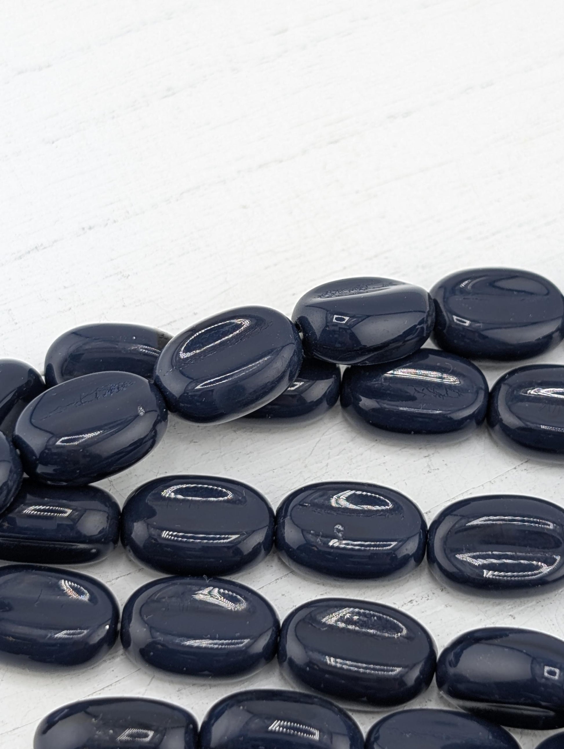 a collection of dark blue, round stones or beads arranged on a white surface.