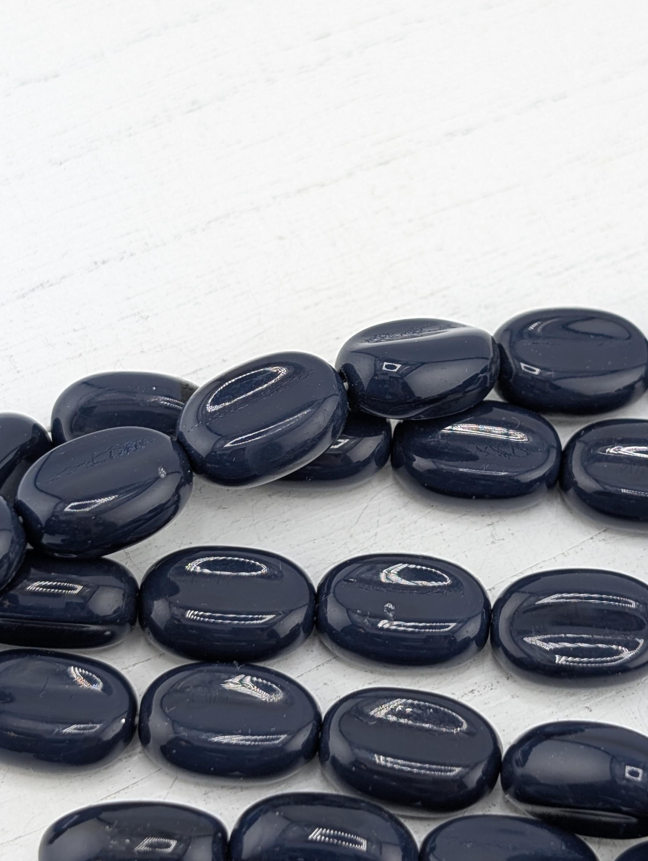 a collection of dark blue, round stones or beads arranged on a white surface.