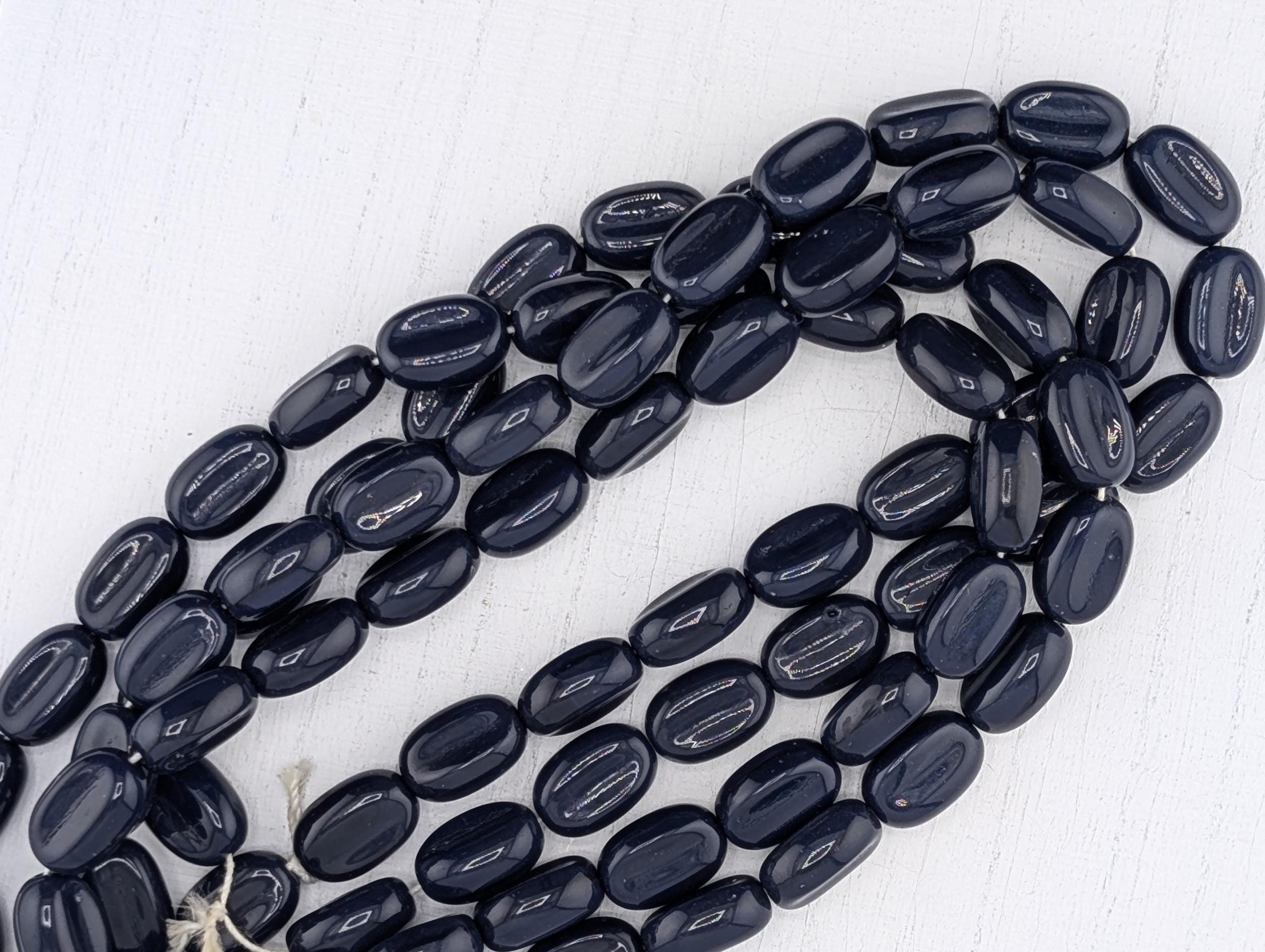A collection of dark blue beads arranged in a circular pattern on a white background.
