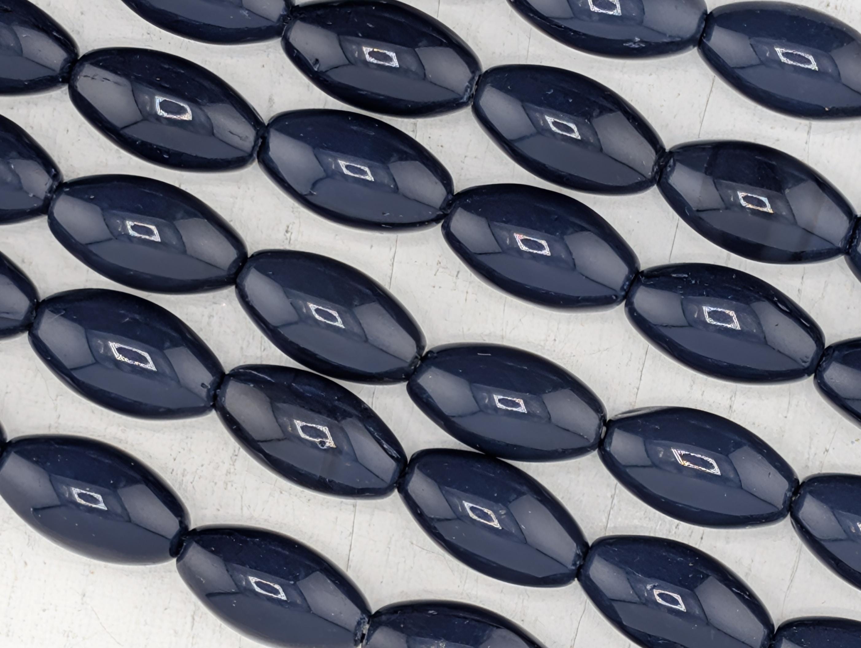 a collection of dark blue beads arranged in a repeating pattern, with some beads having small white accents.