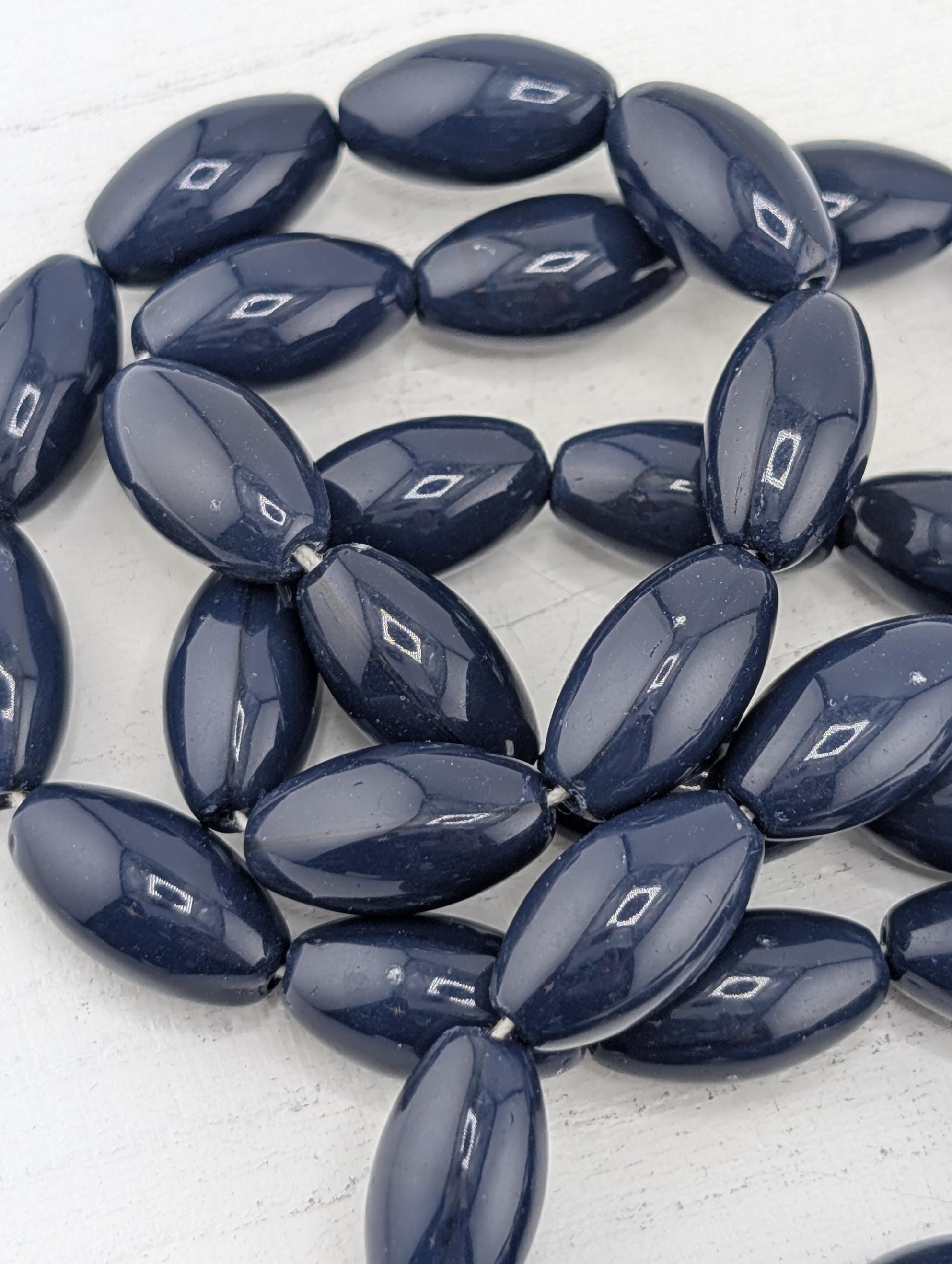 a collection of dark blue beads arranged in a circular pattern on a white surface.