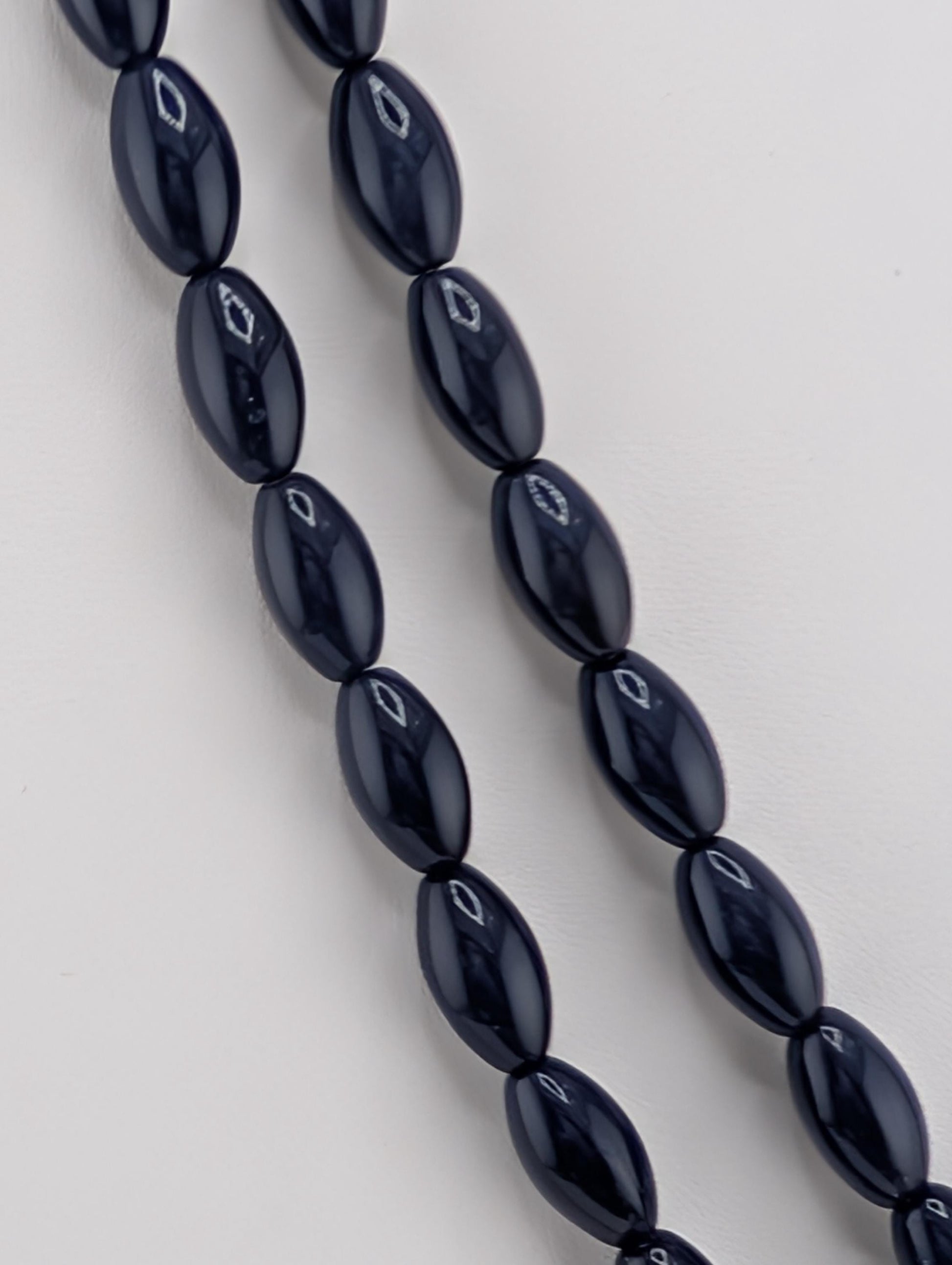 A close-up view of a necklace composed of numerous dark blue beads arranged in a row.