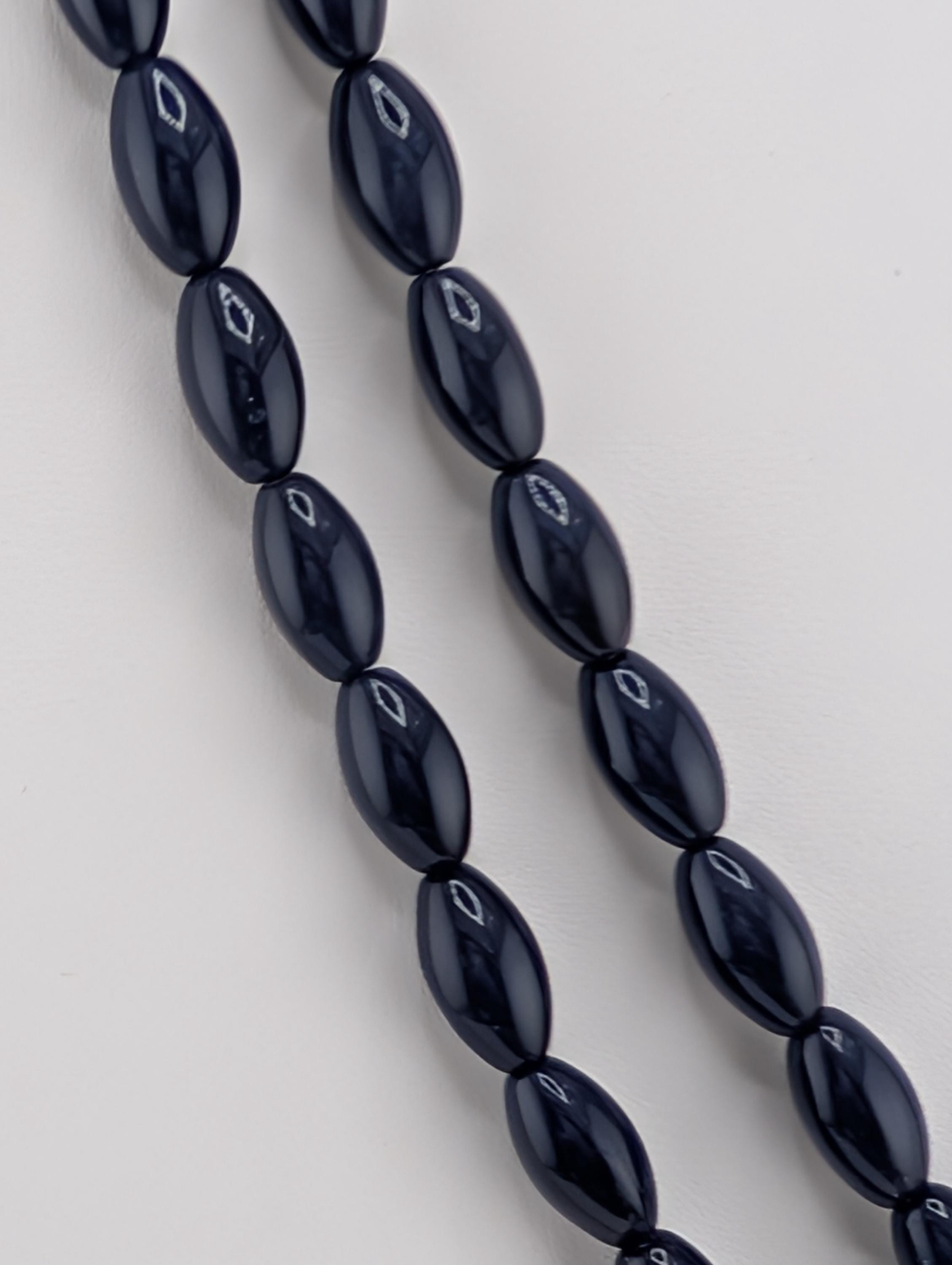 A close-up view of a necklace composed of numerous dark blue beads arranged in a row.