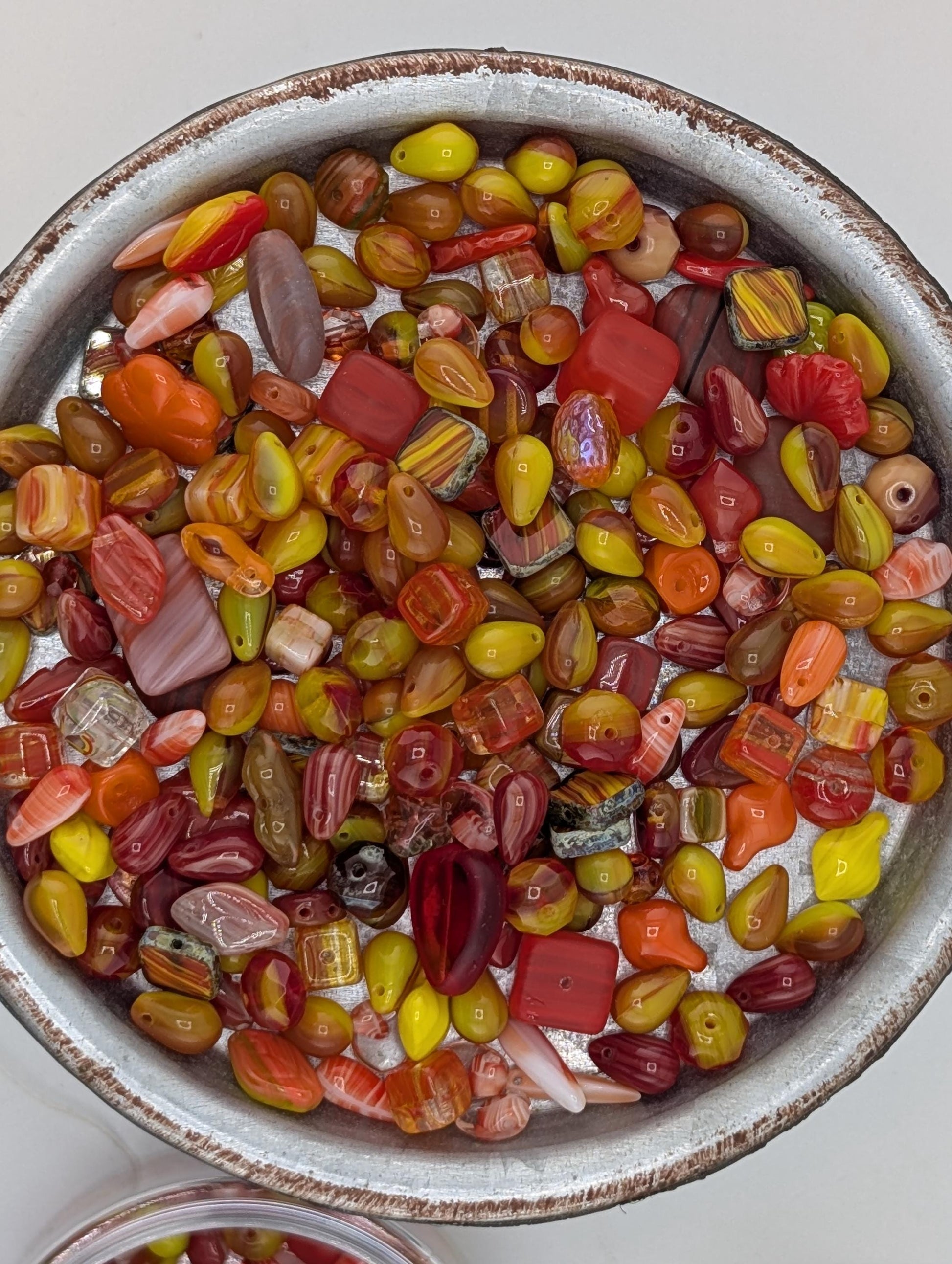 A bowl filled with a variety of colorful beads, including red, orange, yellow, and green beads, creating a vibrant and visually appealing display.