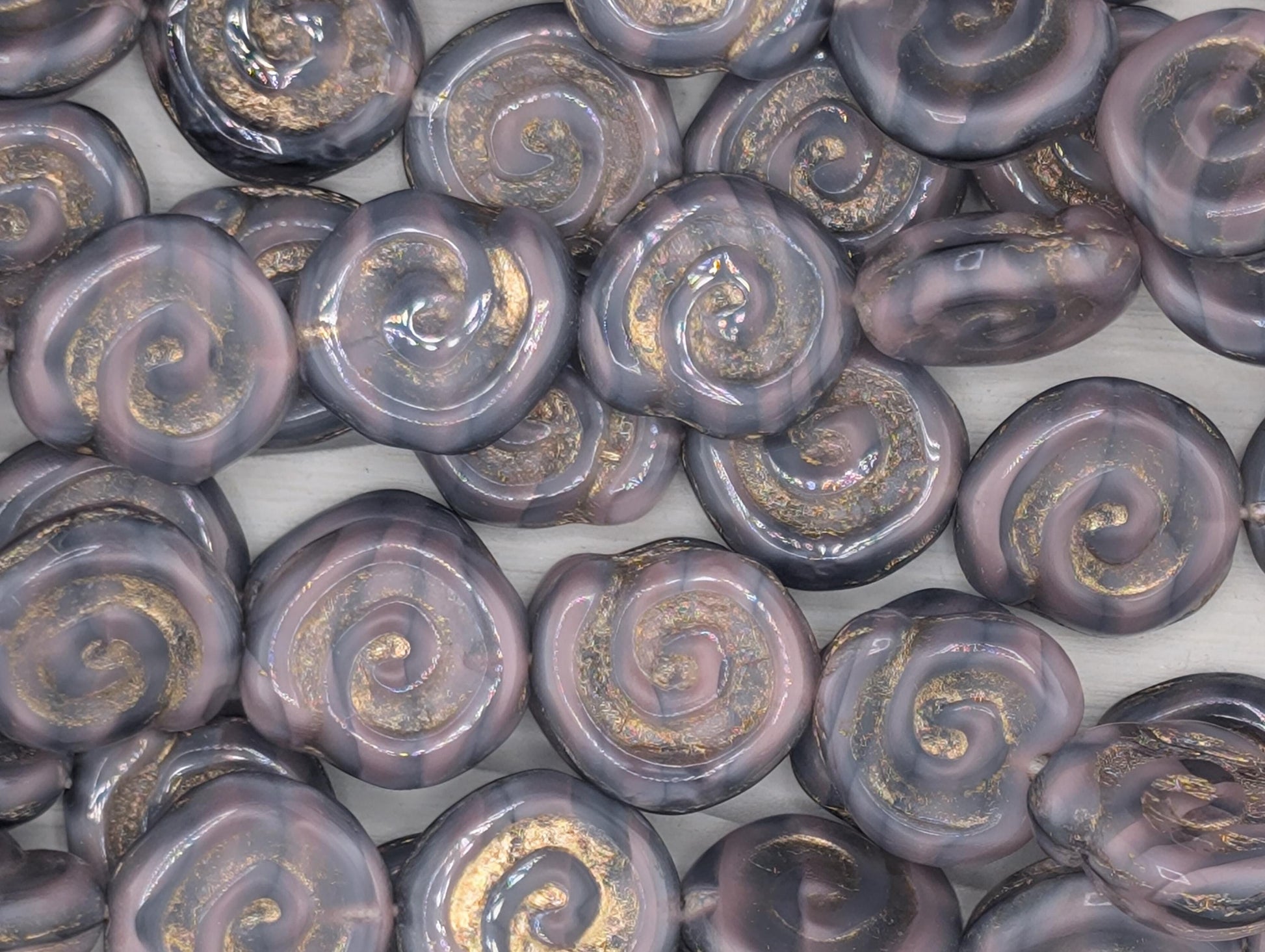 a collection of spiral-shaped objects with a dark purple and gold color scheme, arranged in a grid-like pattern.