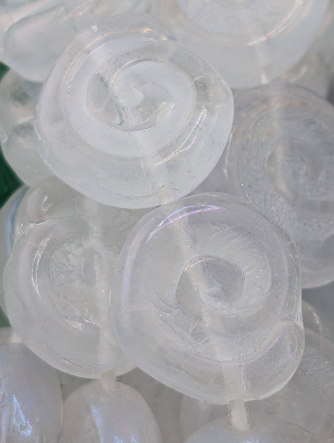 a collection of clear, spiral-shaped beads arranged in rows on a dark surface.