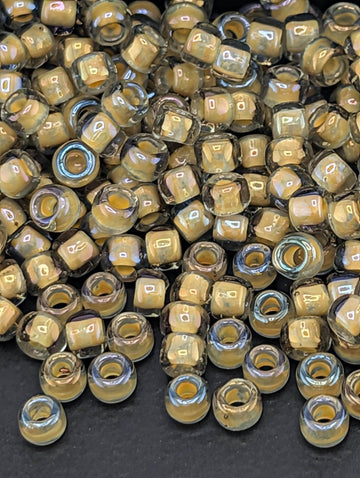 a large pile of small, clear beads in various shades of yellow and brown, scattered on a dark surface.