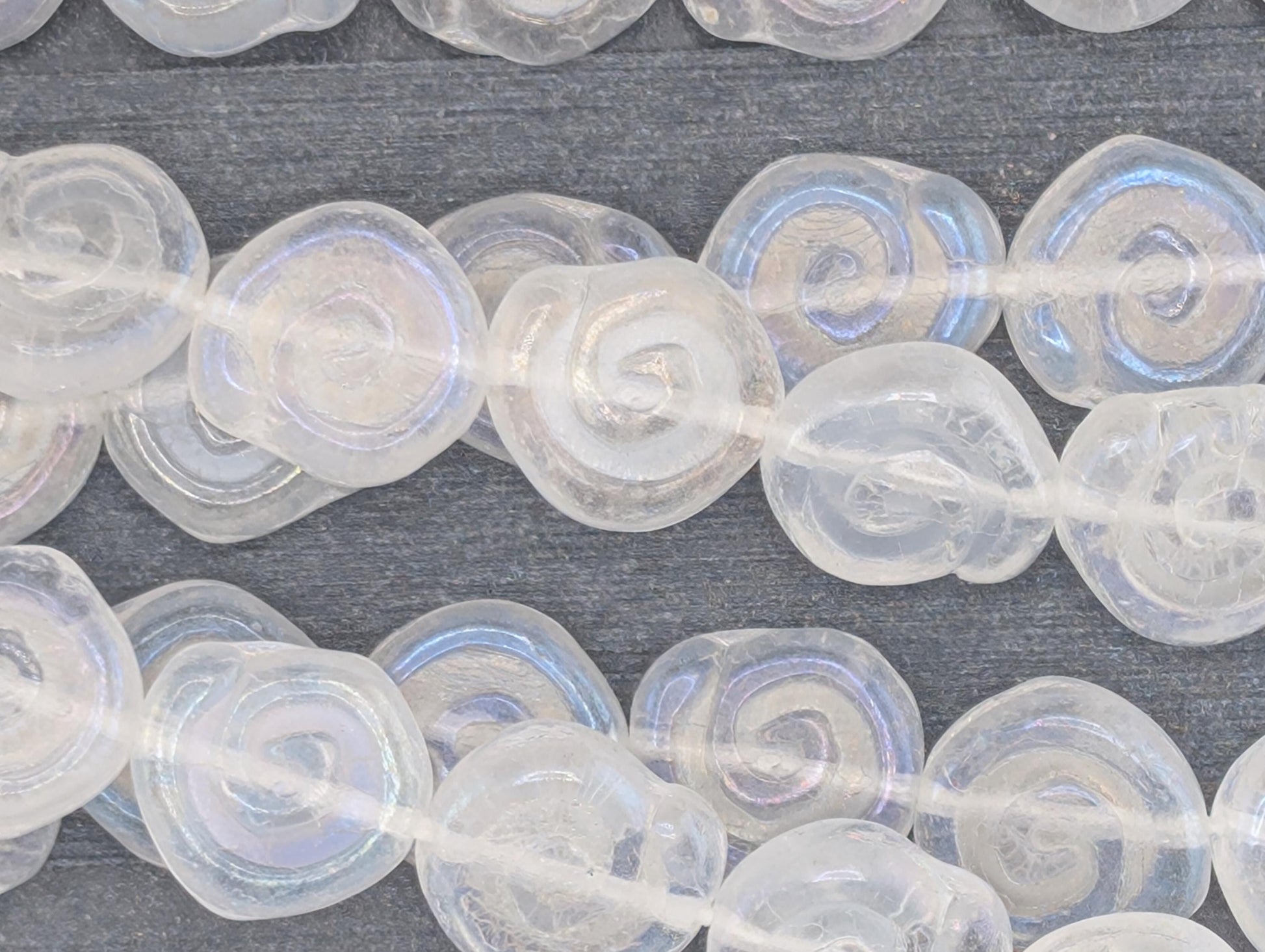 a collection of clear, spiral-shaped beads arranged in rows on a dark surface.