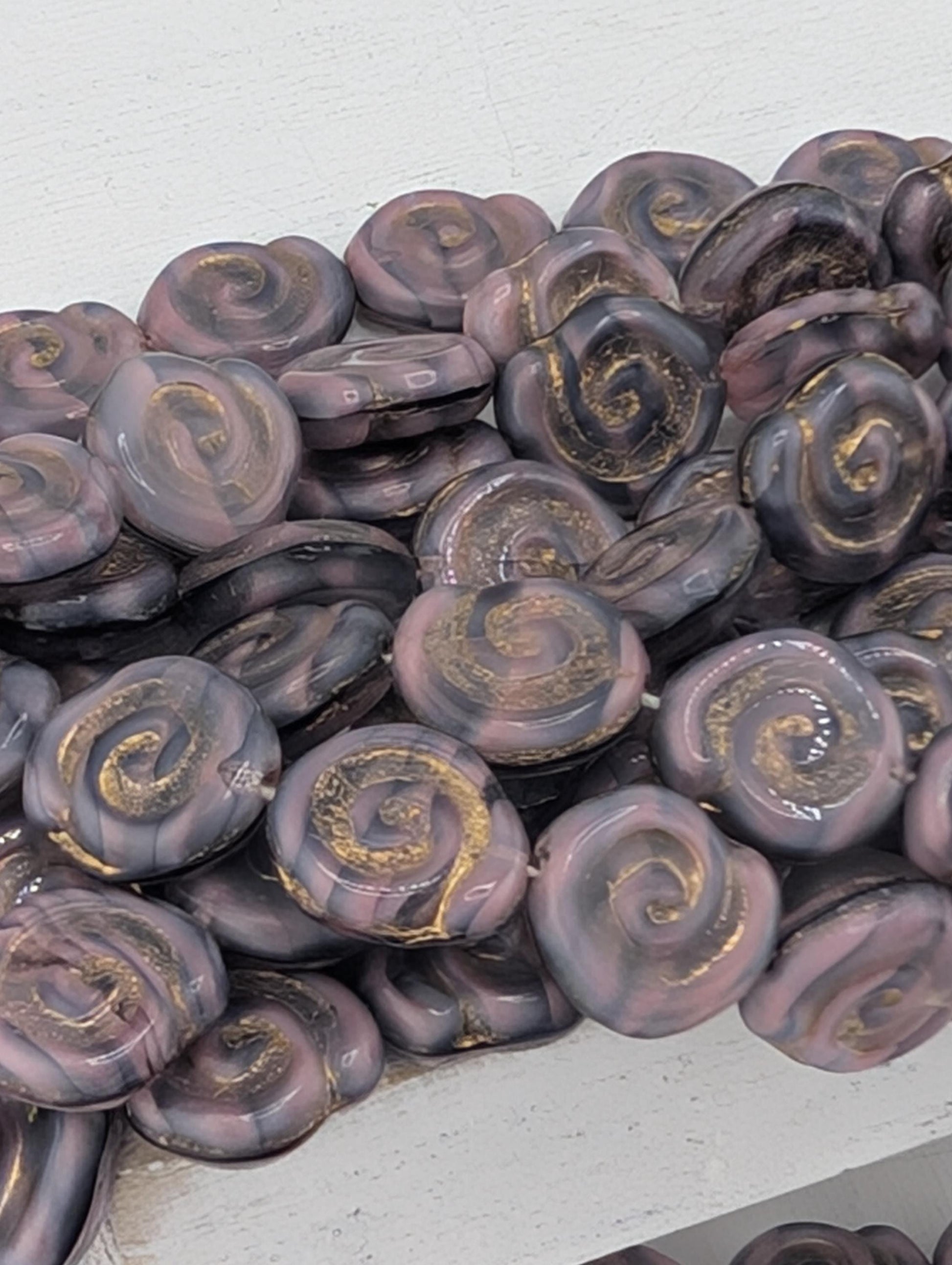 a collection of spiral-shaped beads in various shades of purple and gold, arranged in a visually appealing manner.