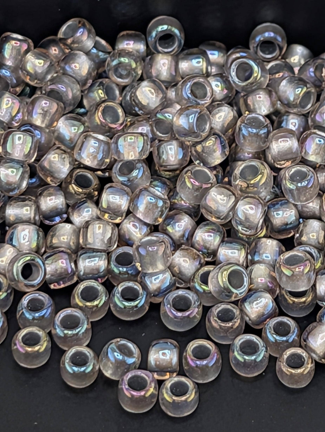 a large pile of clear, iridescent beads scattered on a dark background.