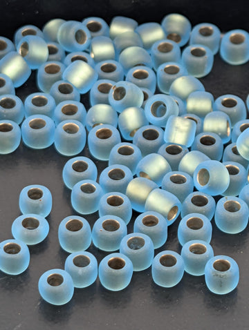 a collection of small, round, blue beads scattered on a dark surface.