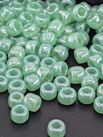 a collection of small, round, green beads scattered on a dark surface.