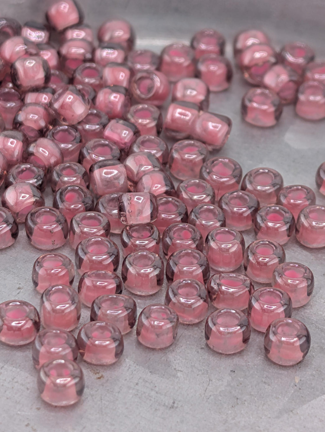 a collection of small, clear beads in shades of pink and purple, scattered across a surface.