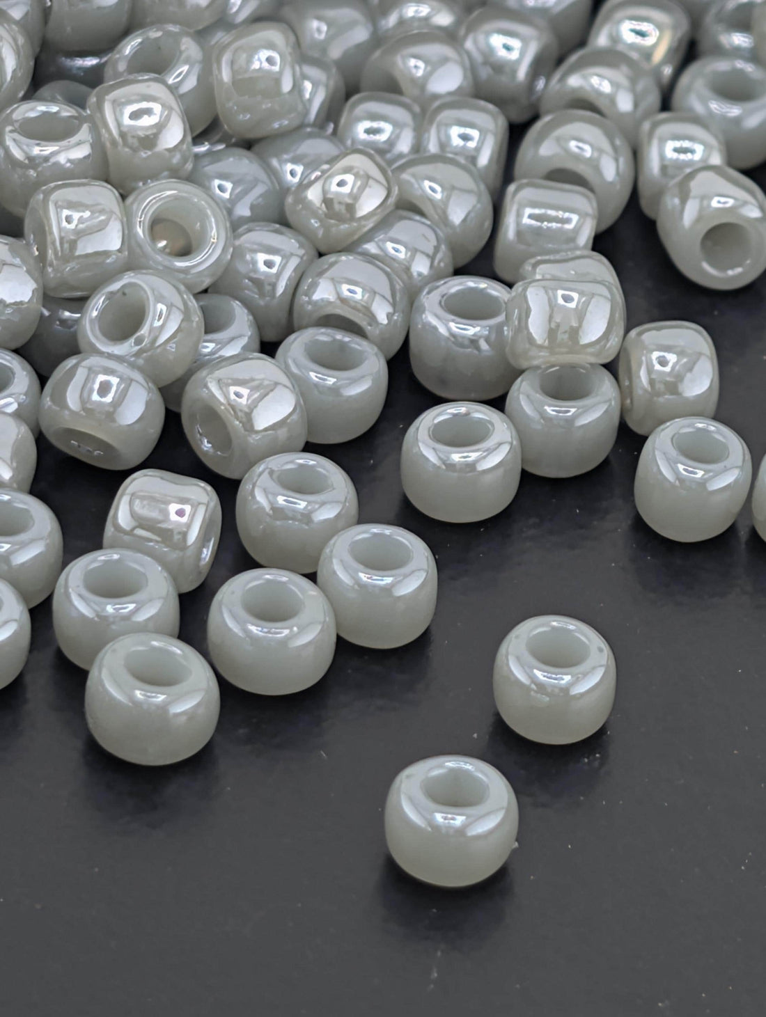 a collection of small, white beads scattered on a dark surface.