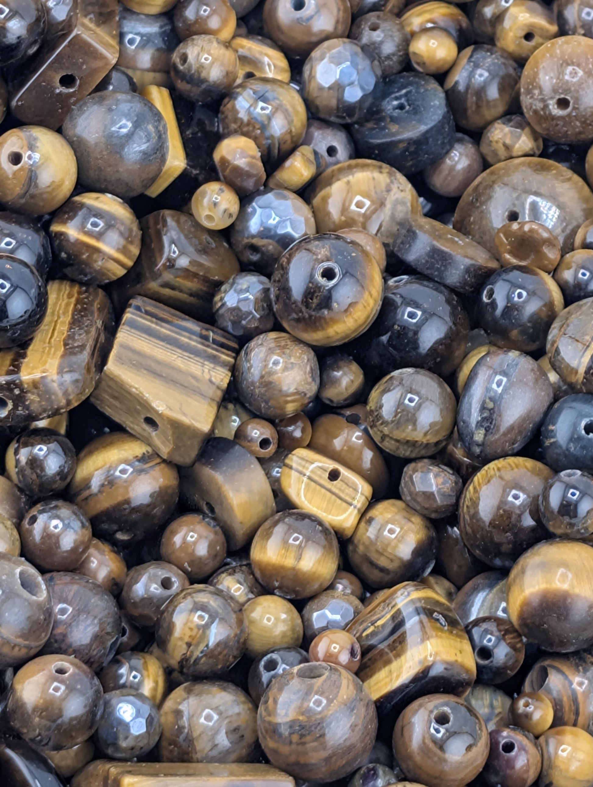 The image is a close-up of various beads and gemstones, including tiger eye beads, arranged in a visually appealing manner.