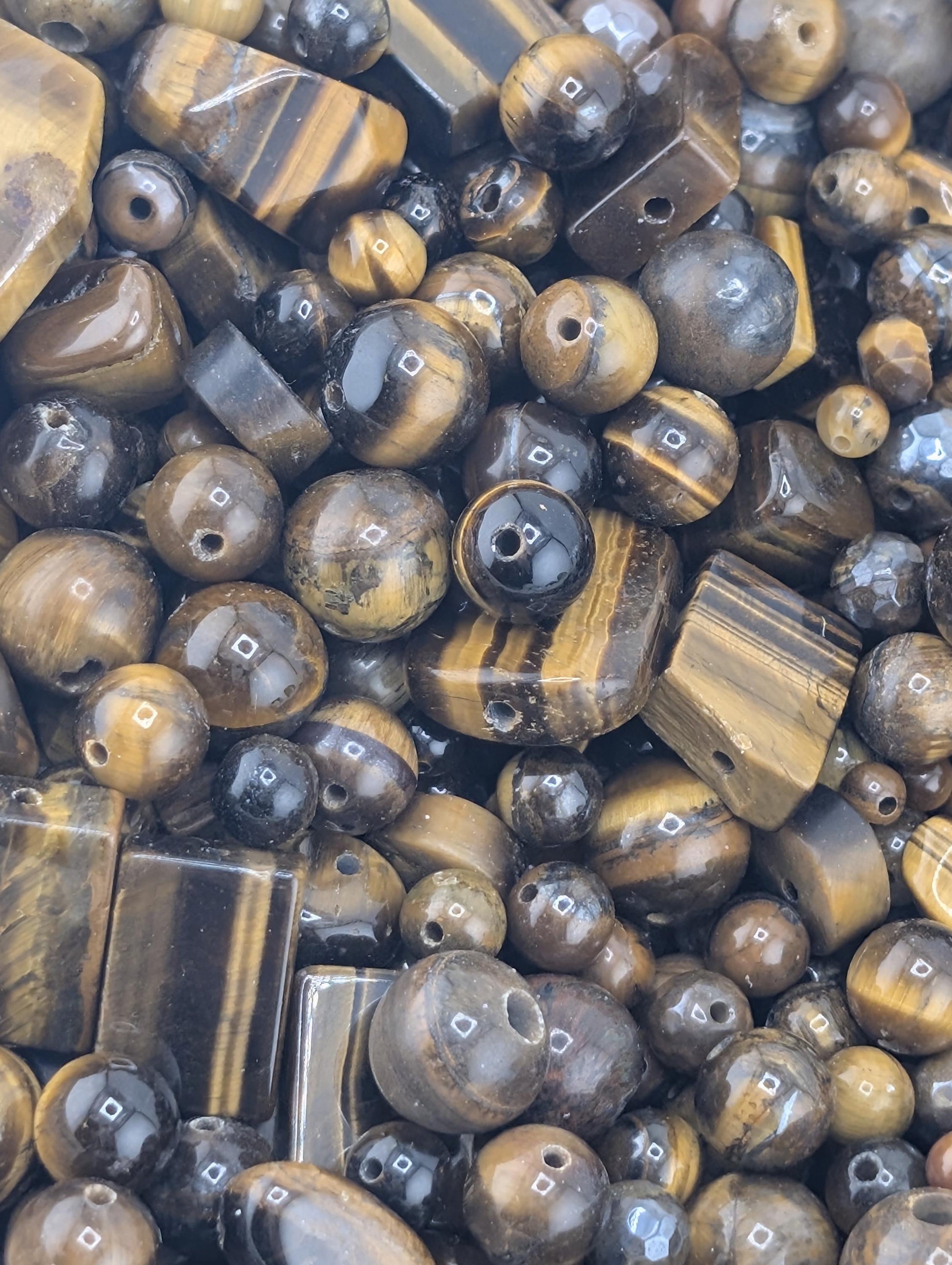 The image is a close-up of various beads and stones, including tiger eye beads, arranged in a visually appealing manner.