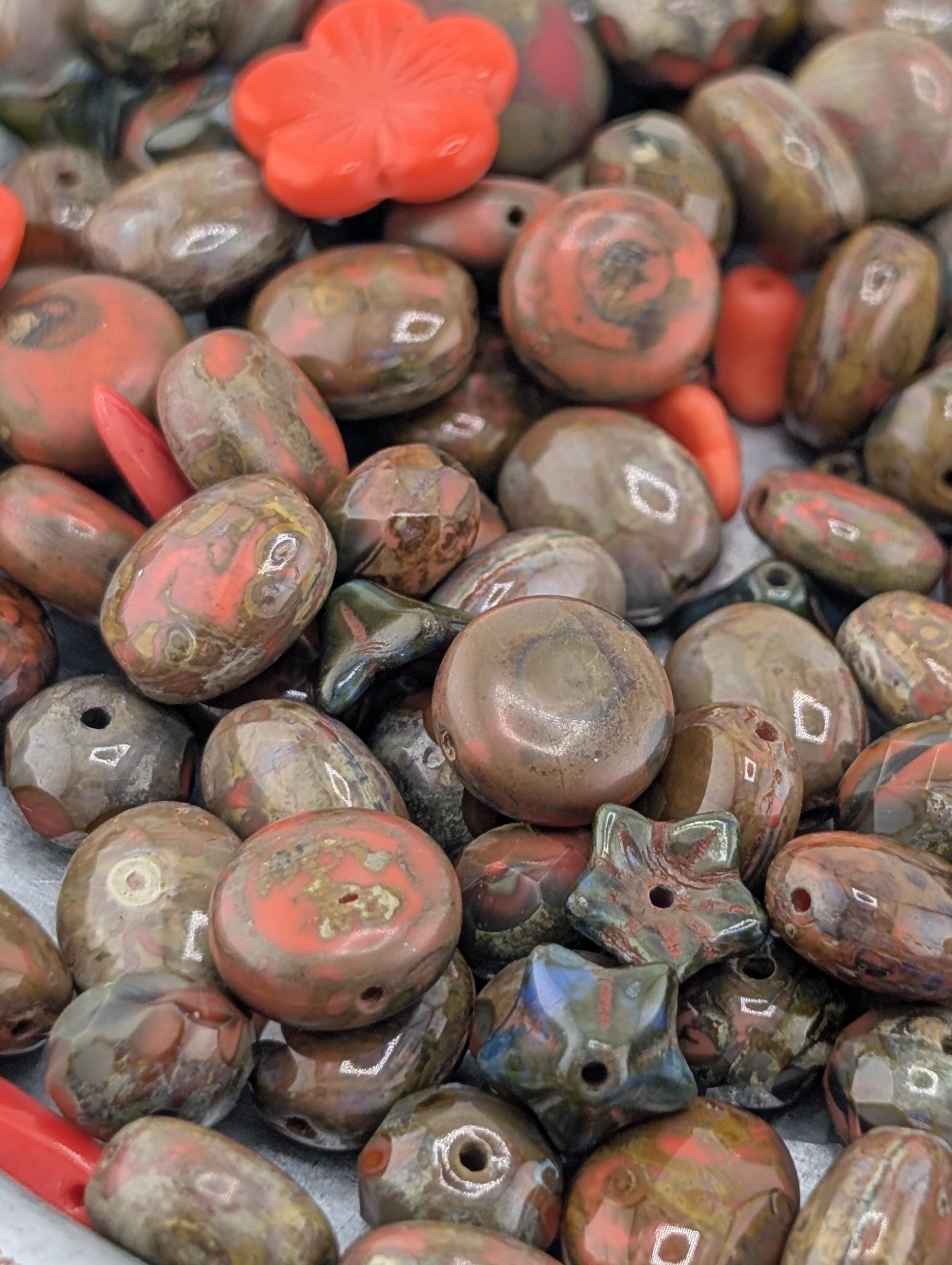 a close-up view of a collection of various colored beads, including red, brown, and green, scattered together.
