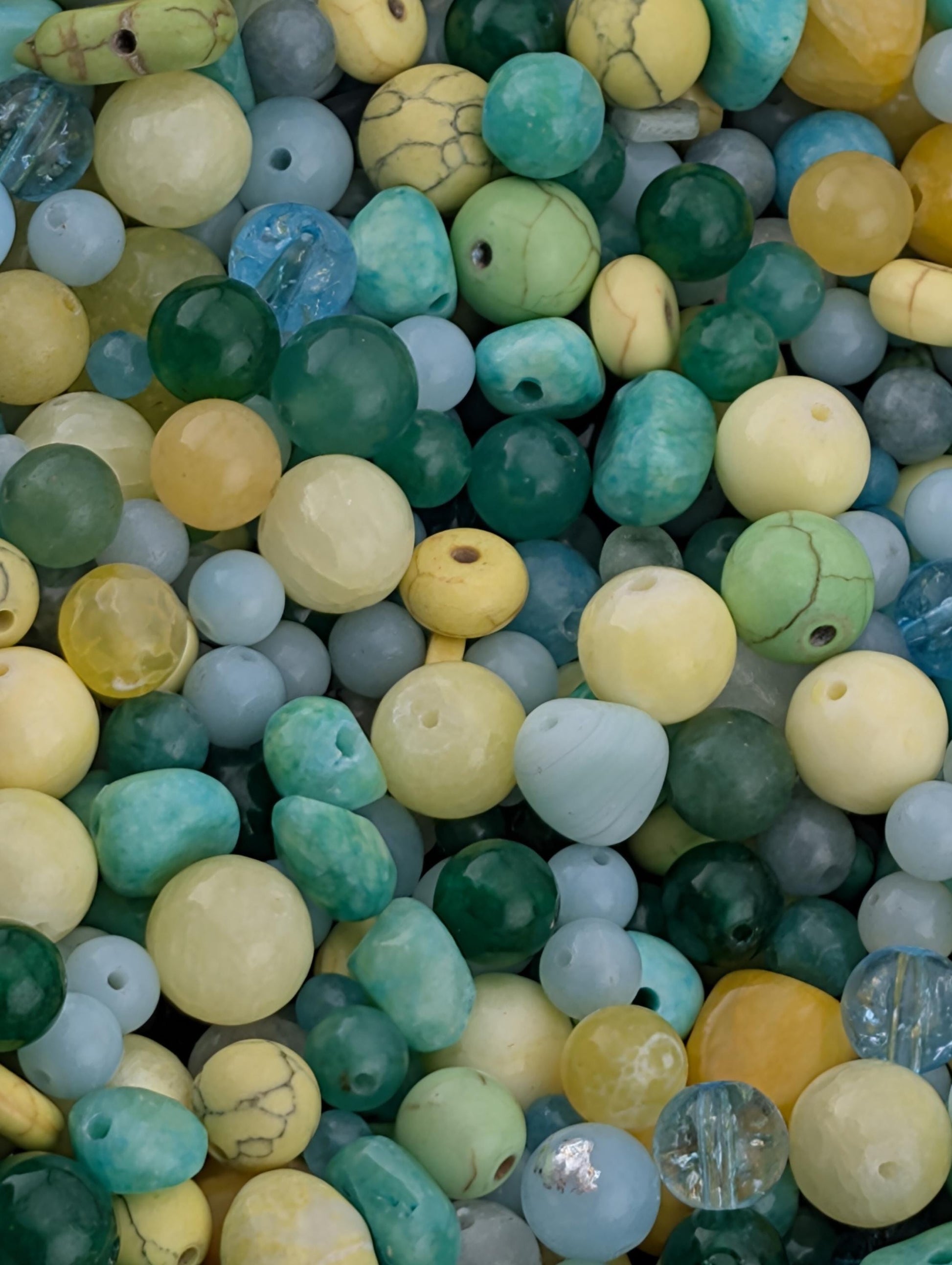 The image is a close-up of a variety of colorful beads, including turquoise, yellow, and green beads, as well as some clear beads.