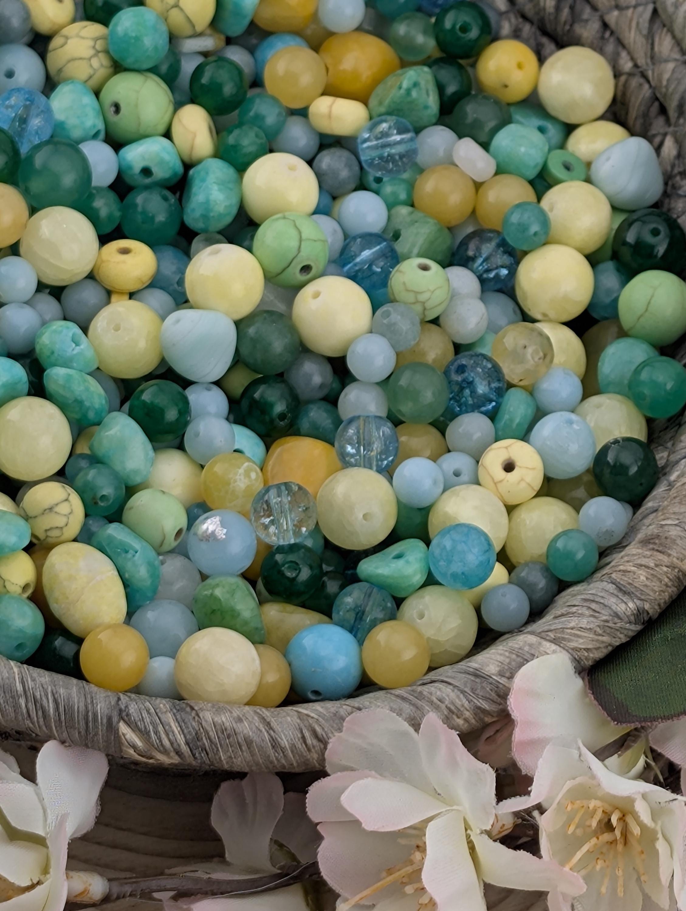a basket filled with various colored beads, including blue, green, yellow, and white beads, as well as some flowers.