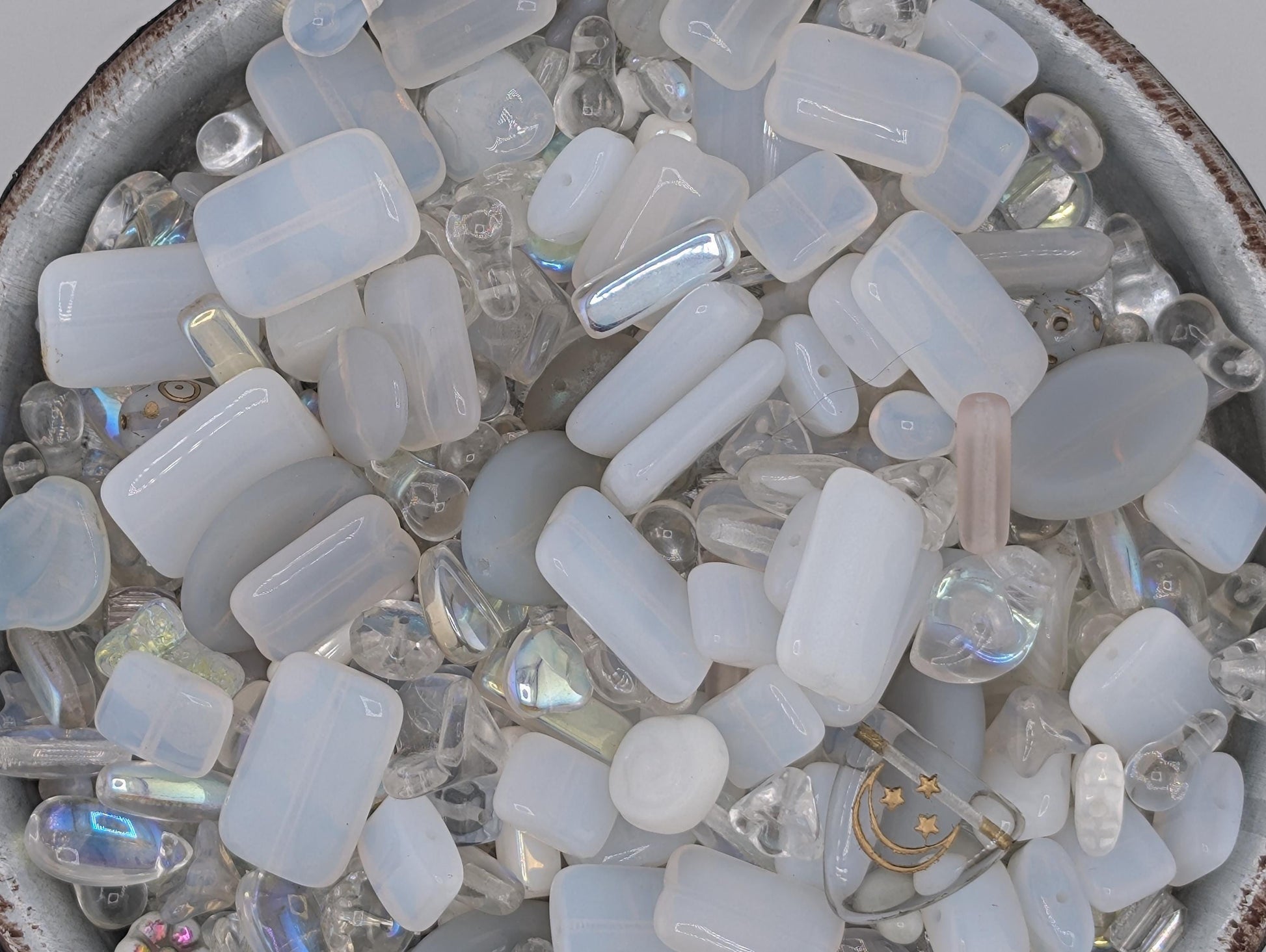 A bowl filled with various clear glass beads and crystals, including clear glass beads, clear glass crystals, and clear glass beads with a metallic sheen.