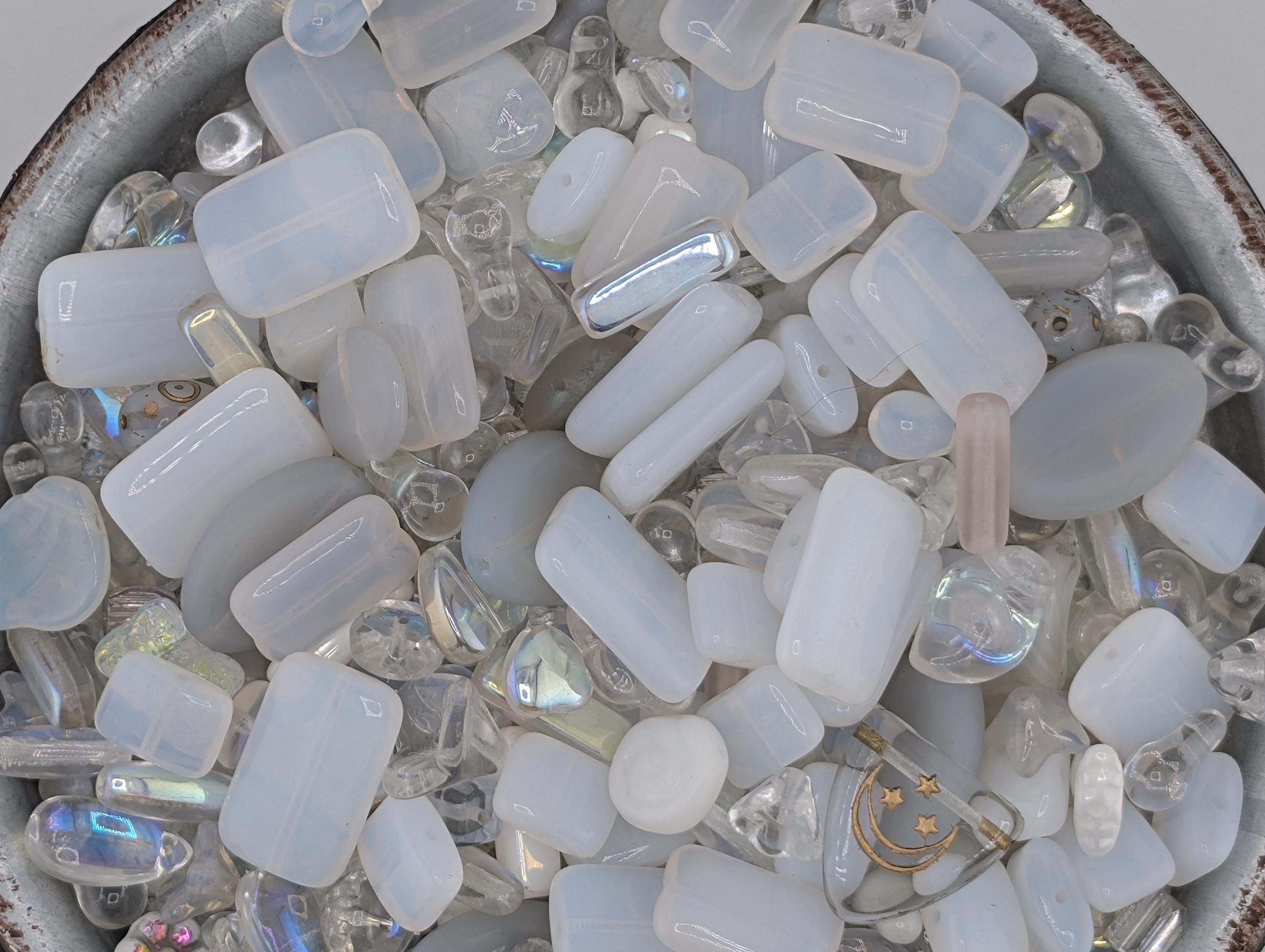 A bowl filled with various clear glass beads and crystals, including clear glass beads, clear glass crystals, and clear glass beads with a metallic sheen.