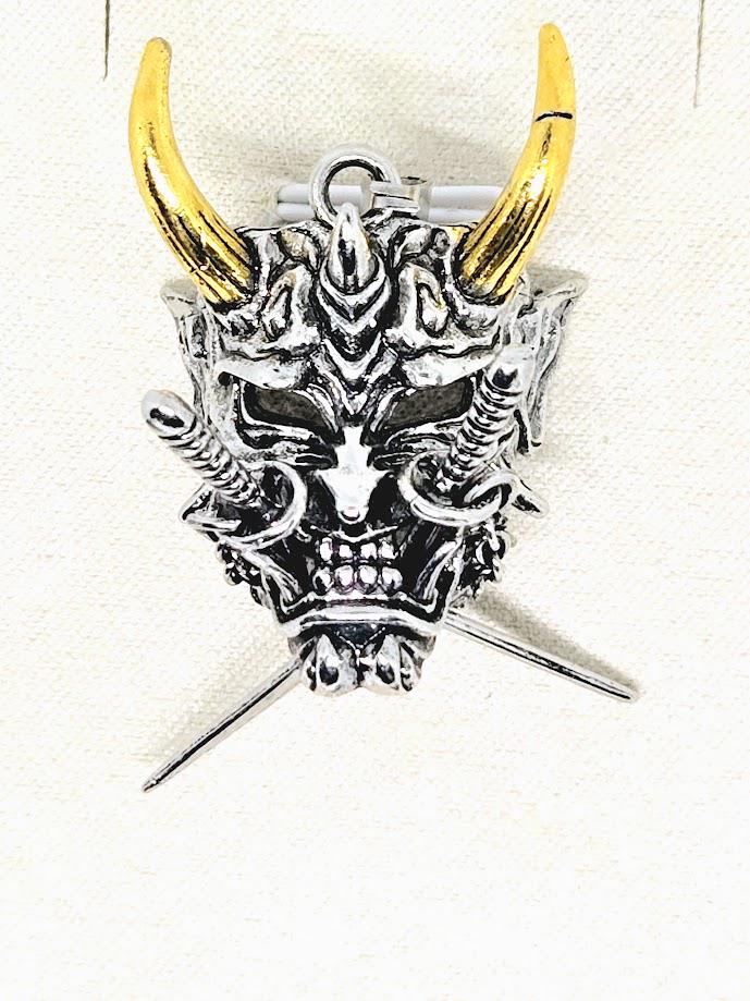 A silver and gold pendant in the shape of a skull with horns, possibly a decorative piece or a piece of jewelry.
